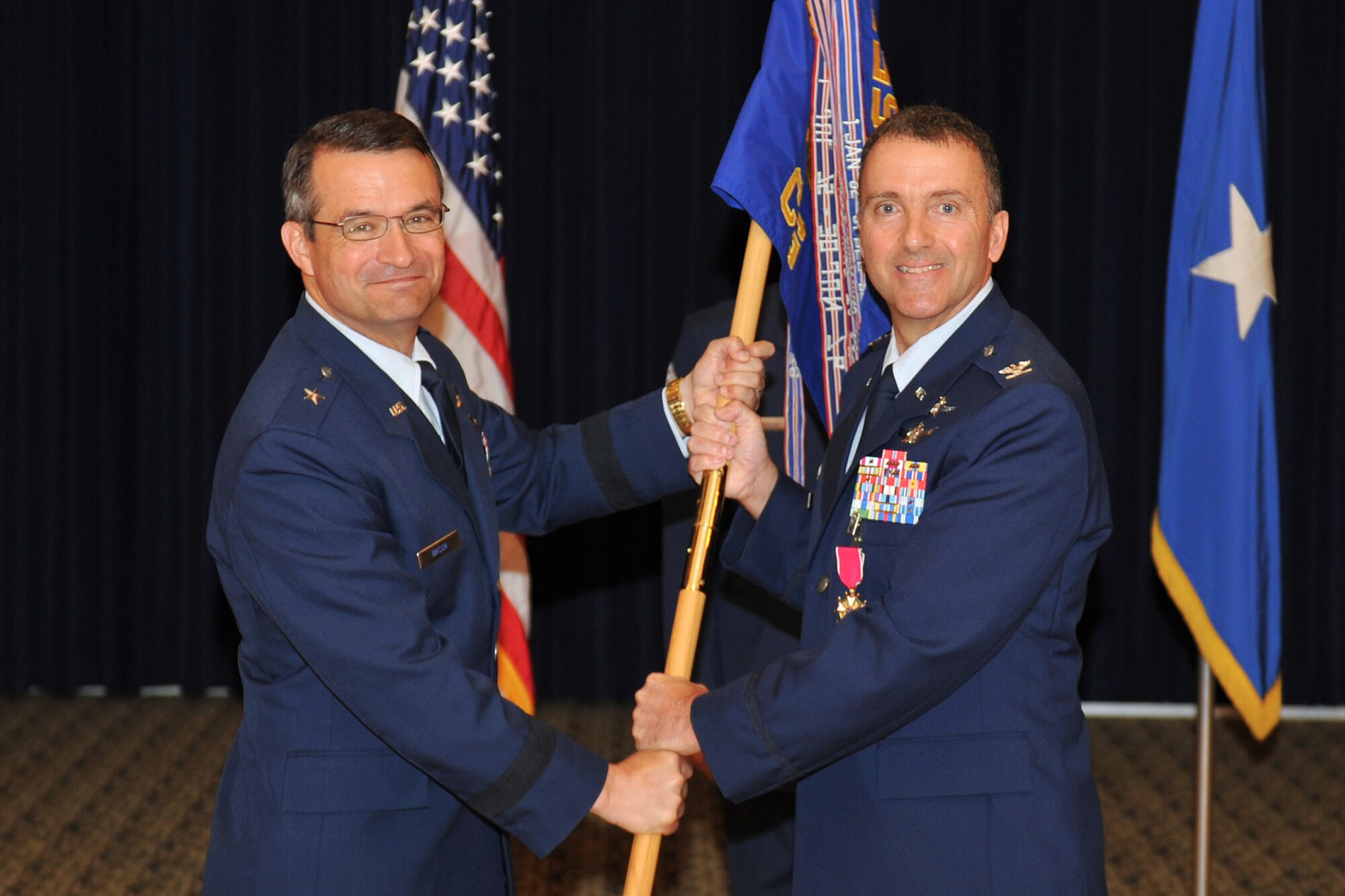 U.S. Air Force Col. Dennis W. Lisherness, 55th Communications Group commander, relinquishes command and passes the guidon to Brig. Gen. Donald J. Bacon, 55th Wing commander, during a change of command ceremony inside the Patriot Club on Offutt Air Force Base, Neb., July 19. (U.S. Air Force Photo by Jeff W. Gates/Released)