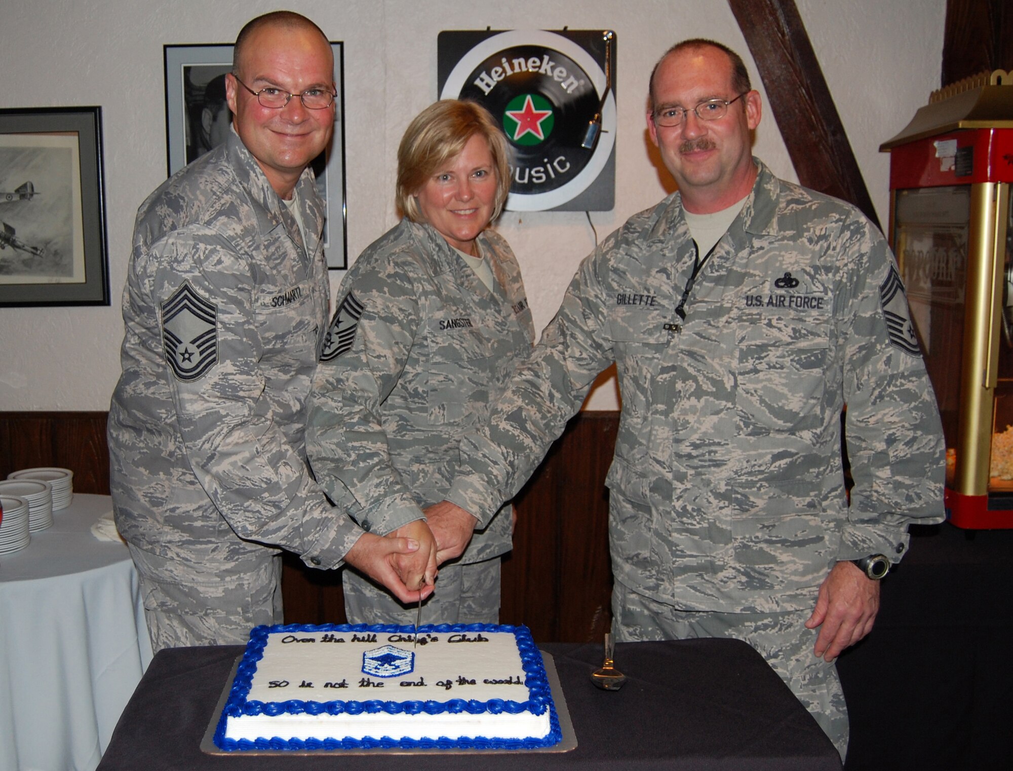 Chief Master Sgt. Barry Schwartz, 55th Operations Group superintendent, Command Chief Master Sgt. Suzan Sangster, 55th Wing command chief, and Chief Master Sgt. Michael Gillette, 55th Aircraft Maintenance Squadron superintendent, cut a birthday cake to mark each other's 50th birthday at the Patriot Club at Offutt Air Force Base, Neb. July 15. All three chiefs celebrated their 50th birthday during the month of July. (U.S. Air Force photo by Ryan Hansen/Released)