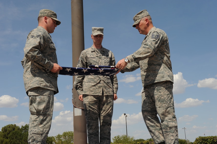 DYESS AIR FORCE BASE, Texas-- Dyess Honor Guardsmen (from left to right) Senior Airman Zachary Montgomery, Staff Sgt. Brandon Hutchinson and Master Sgt. Christopher Ellis fold the flag during a retreat ceremony held at the parade grounds here July 15, 2011. A retreat ceremony signifies the end of a duty day. (U.S. Air Force photo by Airman 1st Class Courtney Moses/Released) 