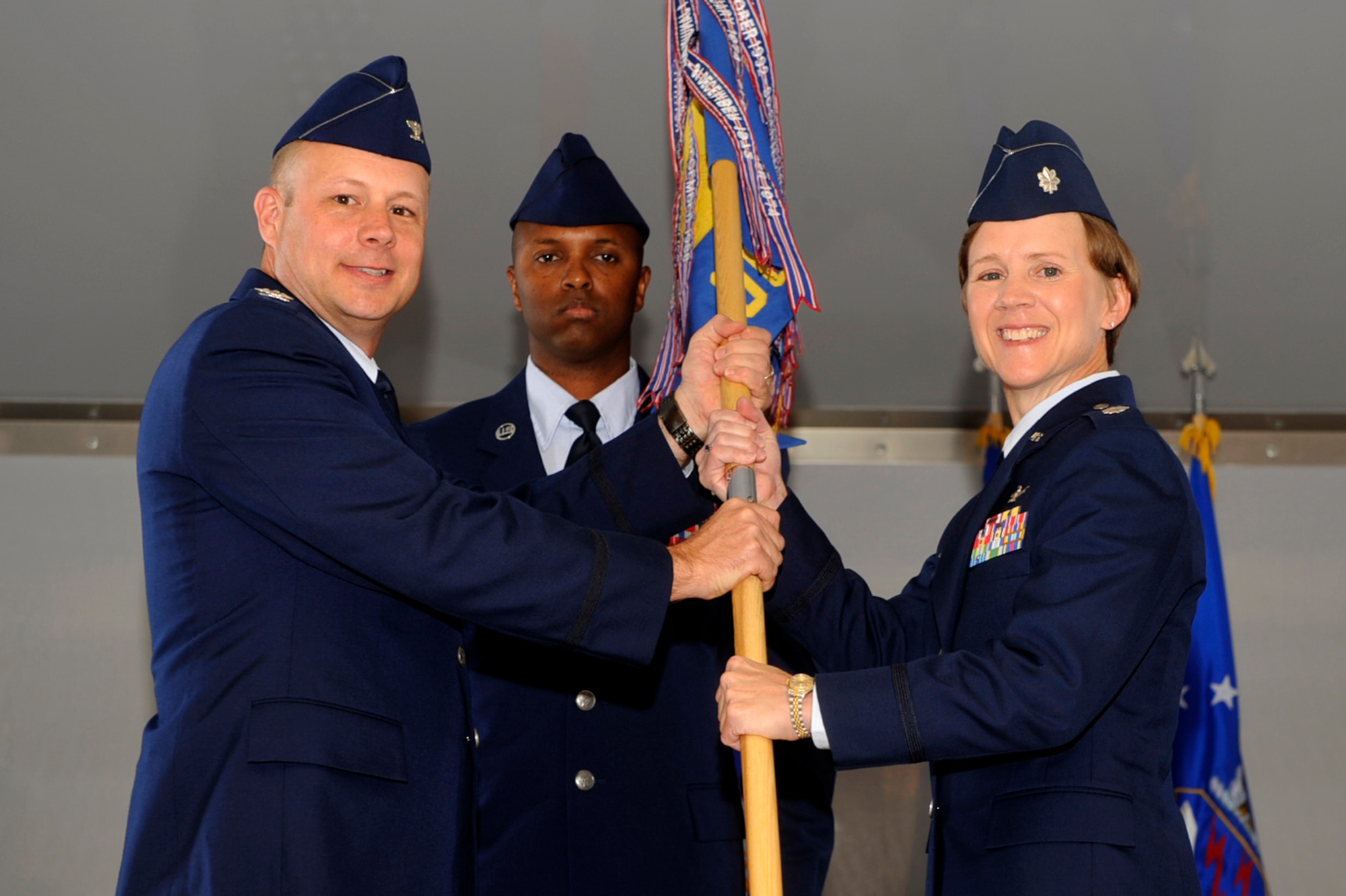 PETERSON AIR FORCE BASE, Colo. – Col. Chris Crawford (left), 21st Space Wing commander, passes the 21st Operations Group guidon to Lt. Col. Jennifer Moore, who took command of the 21st Operations Group July 8, 2011. The 21st OG executes real-time space control, missile warning and missile defense operations to the president, secretary of defense, Joint Chiefs of Staff, combatant commands and foreign allies. The group develops future combat counterspace capabilities in support of theater campaigns. (U.S. Air Force photo/Robb Lingley)