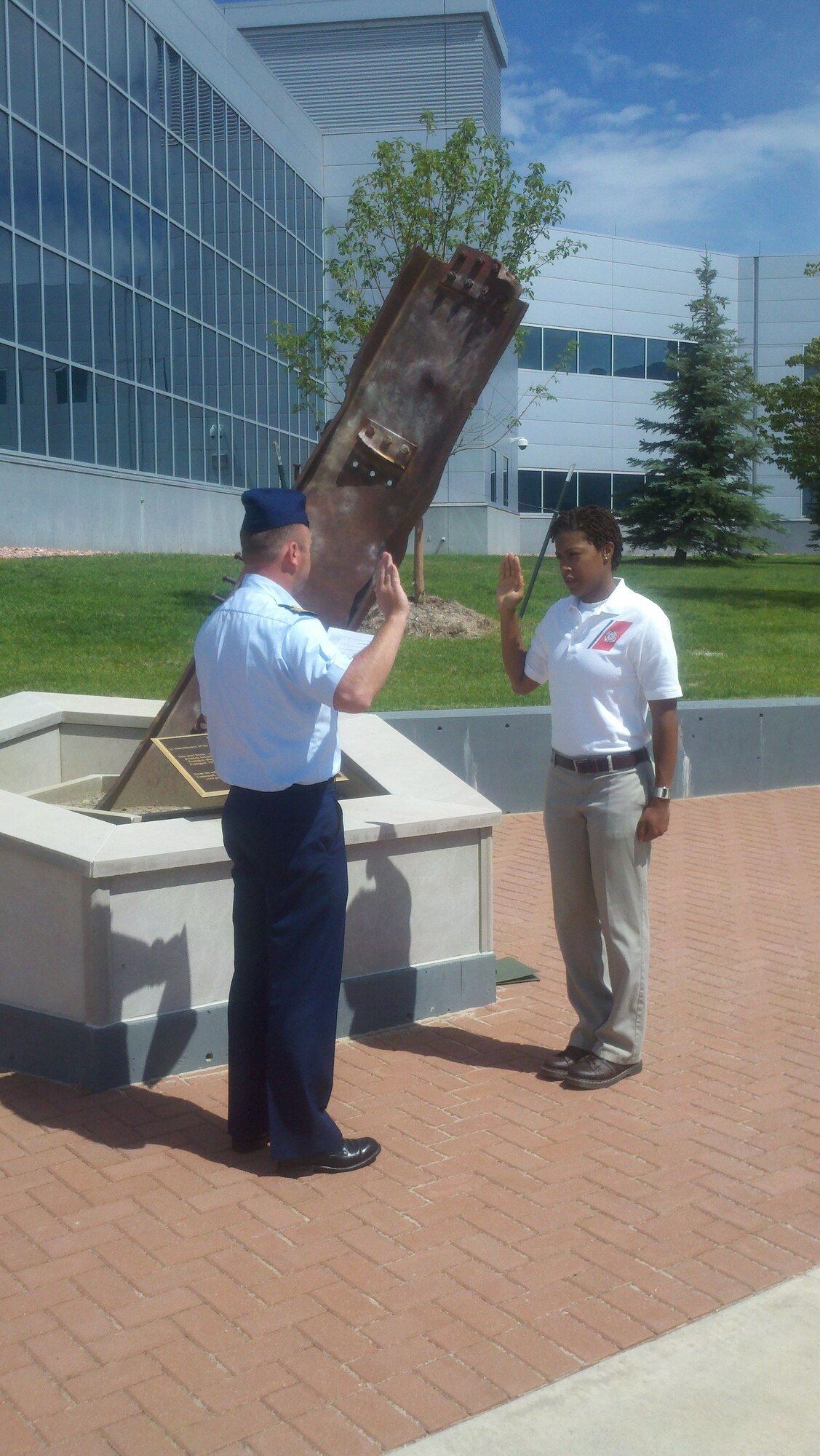 PETERSON AIR FORCE BASE, Colo. - Lt. Cmdr. Kristopher Fegler, U.S. Coast Guard, administers the officer oath July 11, 2011, to former Staff Sgt. Audrey Ested at the 9/11 memorial in front of the North American Aerospace Defense Command and U.S. Northern Command on Peterson AFB. Ested served three years as an Air Force intelligence analyst for the 16th Space Control Squadron, and will now move to Maryland for her transition to ensign as a U.S. Coast Guard intelligence officer. (U.S. Air Force photo/Capt. Rakanem Milligan)