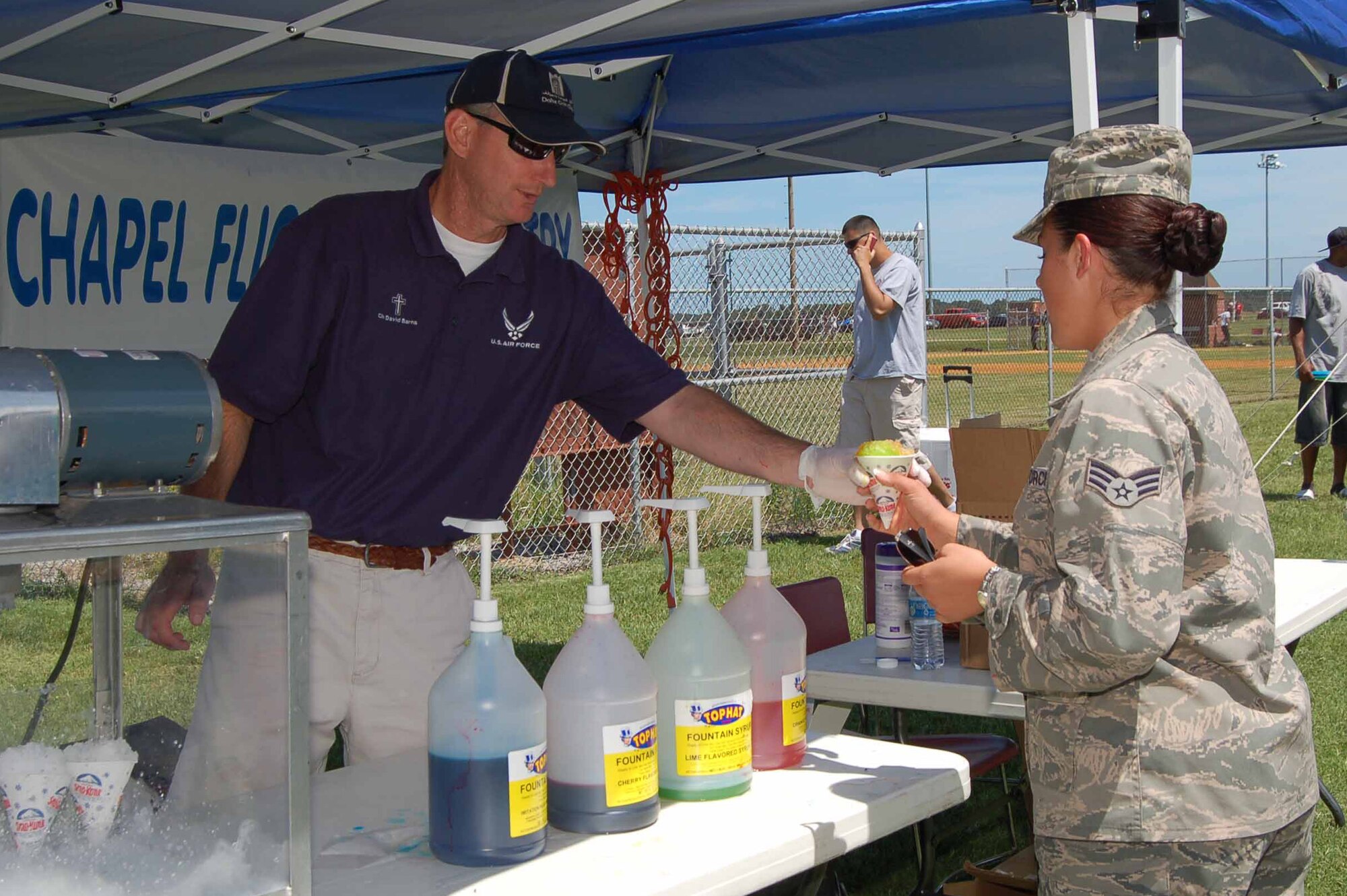 Senior Airman Amanda Williams, 633rd Air Base Wing headquarters knowledge operations manager, takes a snocone from Chaplain (Capt.) David Barns, 633rd Air Base Wing Chapel, at Junior Enlisted Appreciation Day at Langley Air Force Base, Va., July 15, 2011.  Members of the chapel flight line ministry provided the tasty treats for attendees of annual event, which included free food, games, activities and prizes for enlisted members in the grades of E-6 and below and their families. (U.S. Air Force photo by Senior Master Sgt. Anna Hayman/Released)  