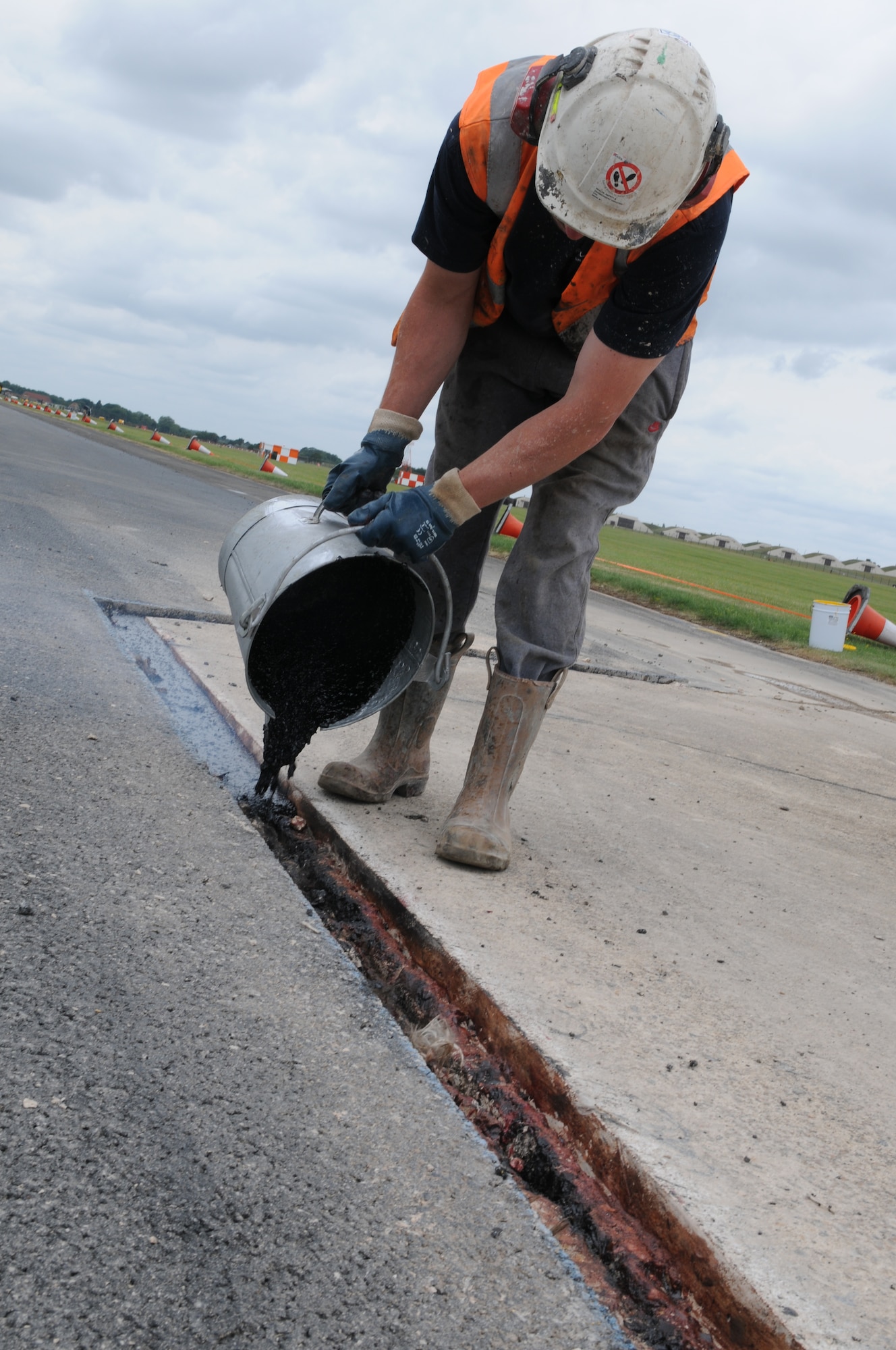 ROYAL AIR FORCE LAKENHEATH, England - Ray Bundy, Allied Drilling construction worker, pours out a tar mixture on the flight line on July 14, 2011.  The runway closure was part of a three year plan to renovate the entire flightline. It was completed on July 18, 2011. The jets were stationed at RAF Mildenhall for 17 days during the last phase.  (U.S. Air Force photo/Airman Cory Payne)