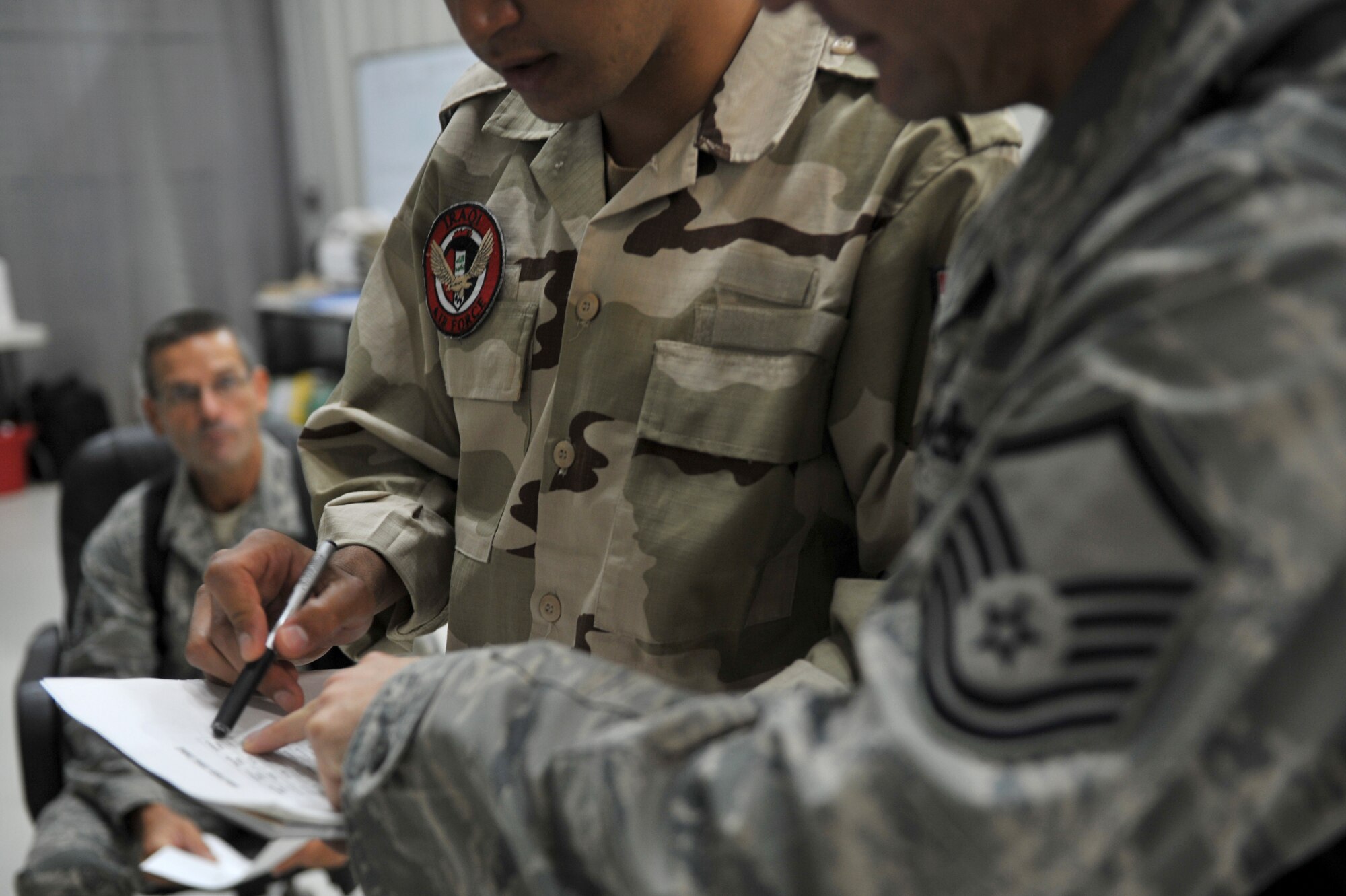 Master Sgt. Vince Clevinger (foreground), 721st Air Expeditionary Advisory Squadron, avionics air advisor, interacts with Iraqi Army Aviation Command students during a Technical English tutoring class, Taji Air Base, Iraq, July 13, 2011. Since beginning on June 20th the class has instructed more than 50 Iraqis on basic english, focusing on Iraqi identified needs such as general conversation and technical terms used at work. The 721st AEAS trains, advises and assists Iraqi pilots and maintenance personnel, focusing on sustainability, reliability and interoperability. Clevinger serves as an avionics flight chief at his home unit, the 58th Aircraft Maintenance Squadron, Kirtland Air Force Base, N.M. (U.S. Air Force photo/Staff Sgt. Mike Meares)



