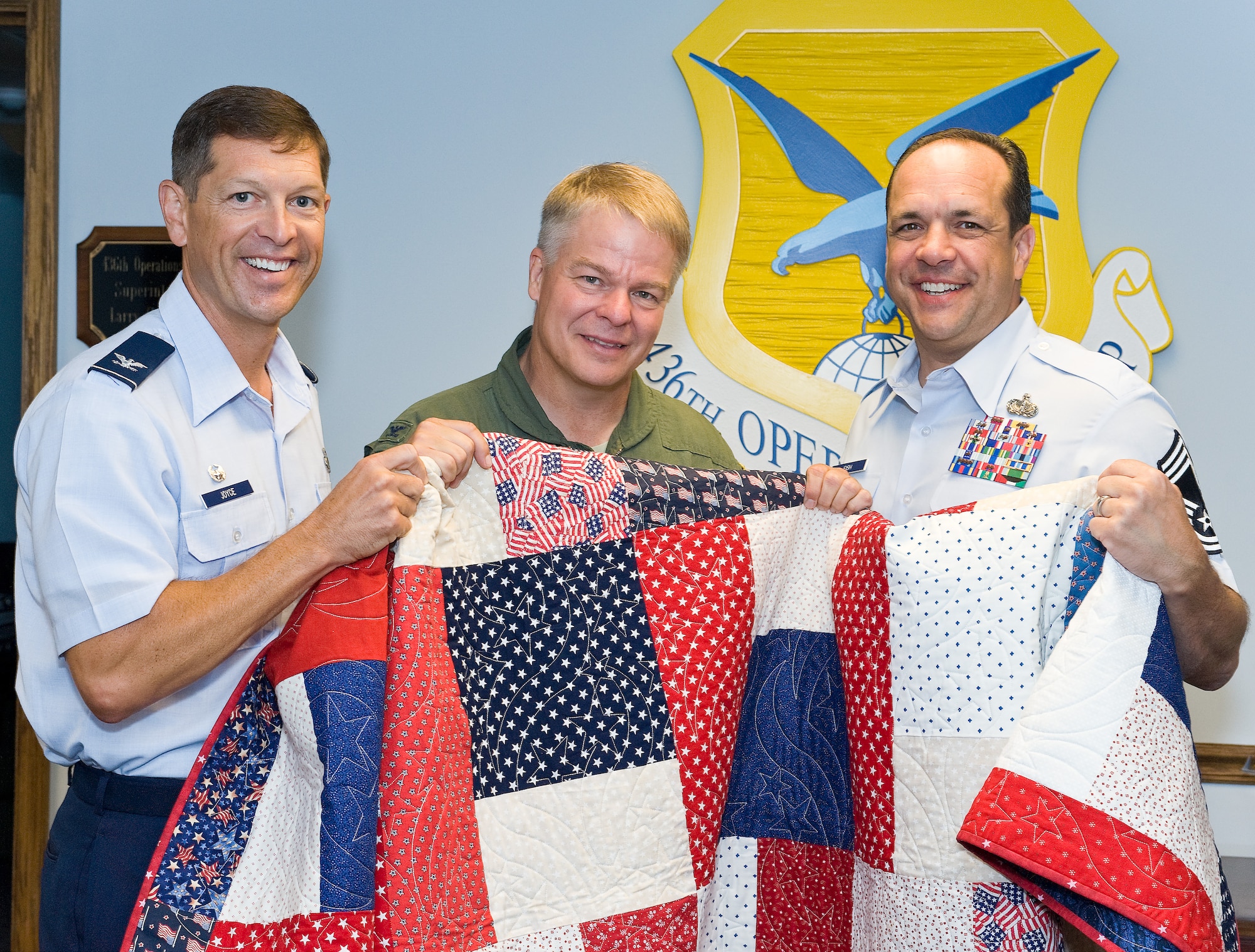 Col. Thomas C. Joyce, Air Force Mortuary Affairs Operations commander, and Chief Master Sgt. David Fish, AFMAO chief enlisted manager, present a Quilt of Valor to Col. David Hafer, 436th Operations Group commander, on behalf of the Quilt of Valor Foundation July 18, 2011. Hafer served as a dignified transfer host honoring fallen servicemembers during his tour at Dover Air Force Base, Del. (U.S. Air Force photo/Roland Balik)