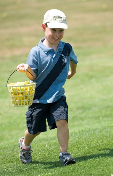 Ethan Burks, son of Lt. Col. William Burks and Susan Burks, runs back to the hitting area of the driving range after collecting a basket of golf balls July 13, 2011, at Dover Air Force Base, Del. Burks participated in the First Tee of Delaware golf program for children and teenagers from kindergarten to 12th grade to teach the etiquette and skills of golf. (U.S. Air Force photo by Airman 1st Class Jacob Morgan)