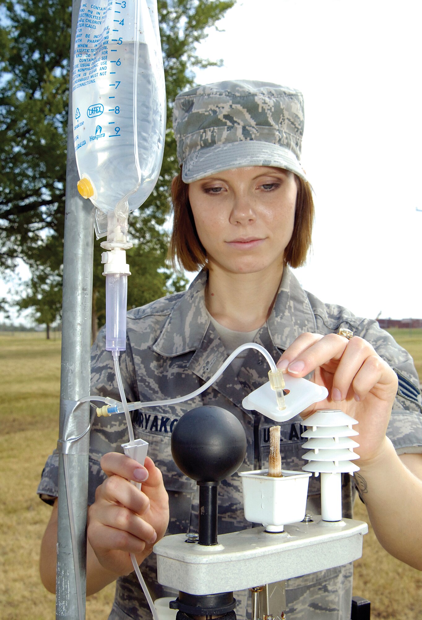 Senior Airman Sophia Hohryakova, 72nd Aerospace Medicine Squadron, Bioenvironmental Engineering Flight, checks the water level in an outdoor Wet Bulb Globe Temperature device that factors humidity, wind and temperature giving readings that determine Tinker’s heat condition levels. The IV bag feeds a slow water drip to the wick in the system which simulates the evaporation of sweat. The unit is permanently installed outside the flight’s offices and sends information to the alerting systems that pop up on Tinker computers and plasma screens. (Air Force photo by Margo Wright)