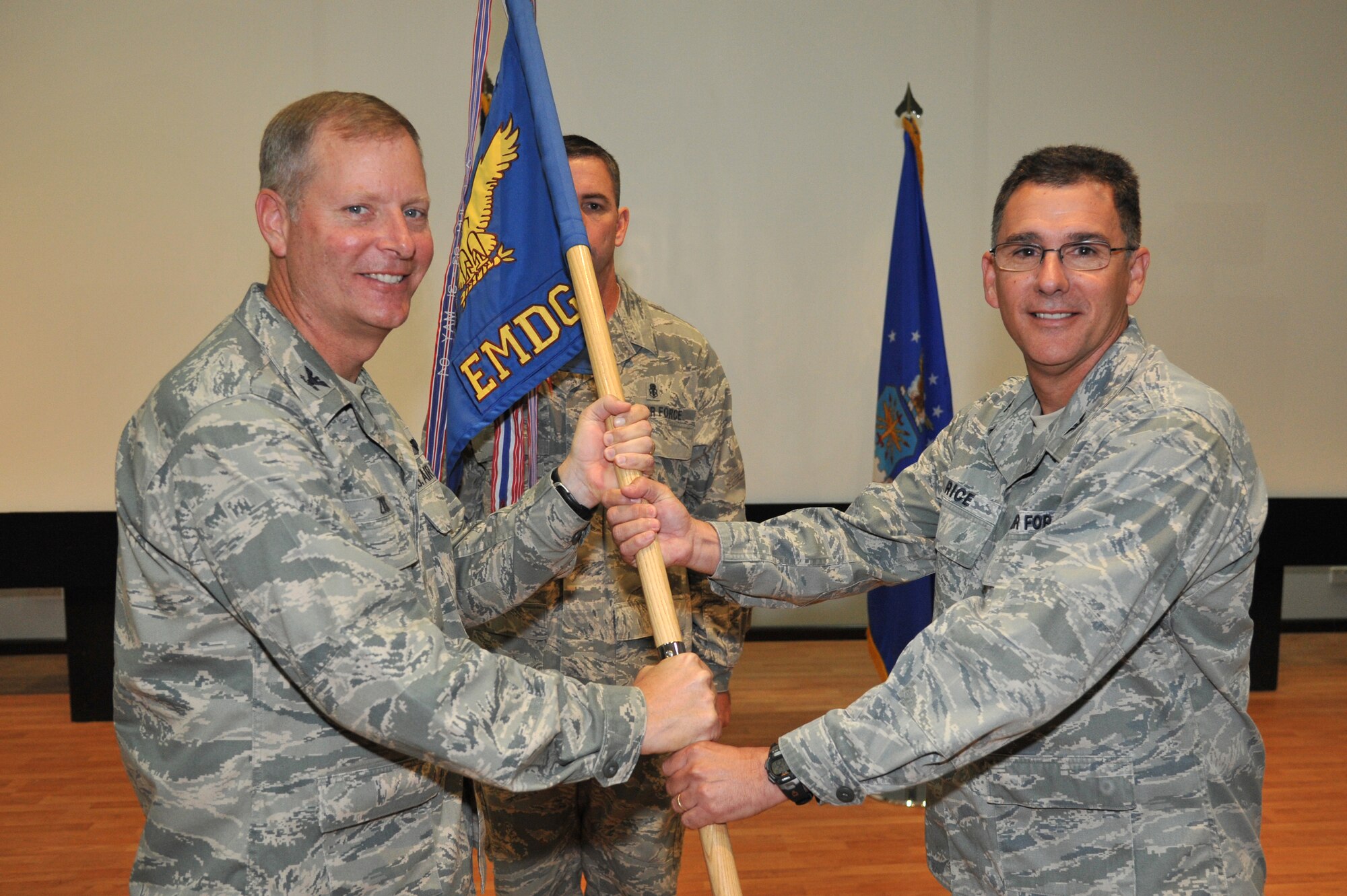 Col. Michael Zick, 386th Air Expeditionary Wing commander, left, passes the 386th Expeditionary Medical Group guide-on to Col. Craig Rice during a change of command ceremony July 17 at an undisclosed location in Southwest Asia. Colonel Rice assumed command of the 386th MDG from Col. Brian Stanton.  (U.S. Air Force photo by Master Sgt. Carlotta Holley)