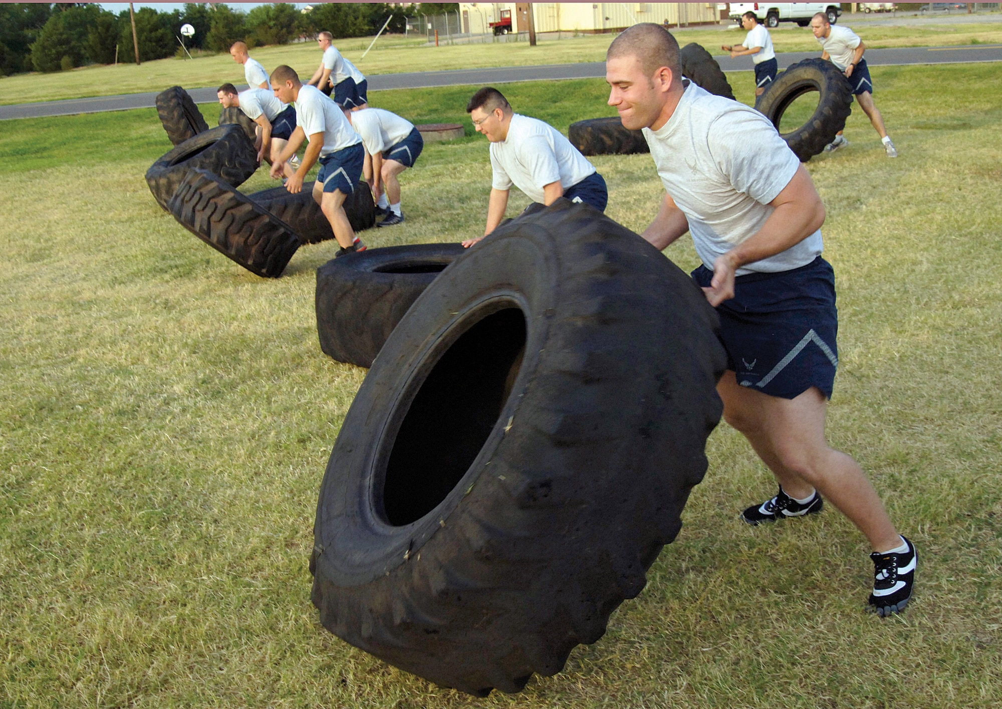 Senior Airman Terry Snyder, front, and members of the 32nd Combat Communications Squadron flip donated truck tires during early morning physical training July 8. Mixing traditional with new ideas to stay fit keeps workouts from becoming easy, repetitive or boring, says 1st Lt. Trevor Steen, PT leader. (Air Force photo by Margo Wright)