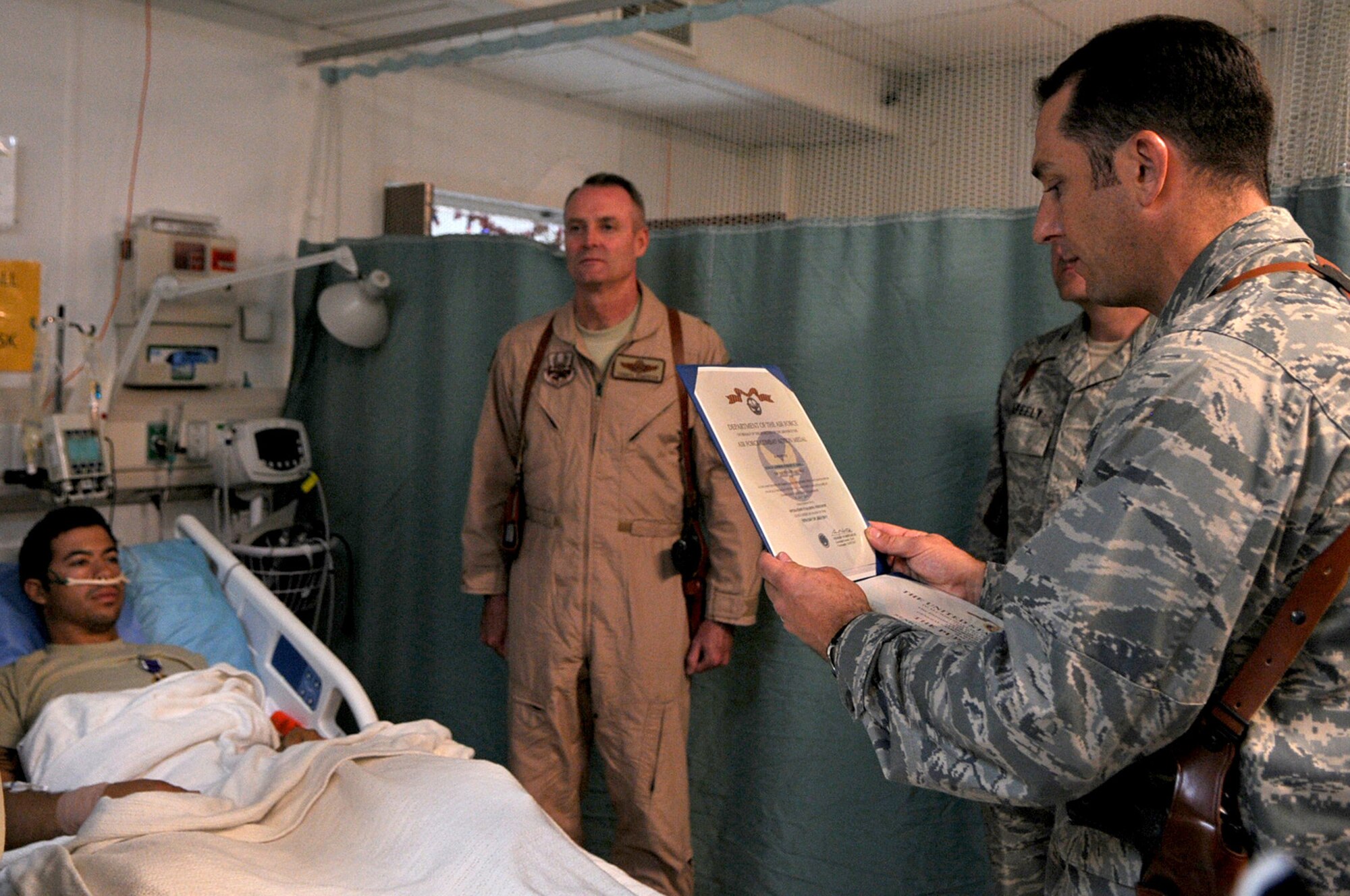BAGRAM AIRFIELD, Afghanistan -- Maj. Joseph Ryther, 455th Expeditionary Air Wing executive officer, reads an Air Force Combat Action Medal Citation to Senior Airman August O’Niell, 46th Expeditionary Rescue Squadron pararescue jumper, during a presentation at Craig Joint Theater Hospital July 16.  O’Niell, deployed from the 58 RQS at Nellis Air Force Base, Nev., suffered gunshot wounds to his lower extremities during a mission to retrieve casualties July 15, 2011. (U.S. Air Force photo/Senior Airman Krista Rose)