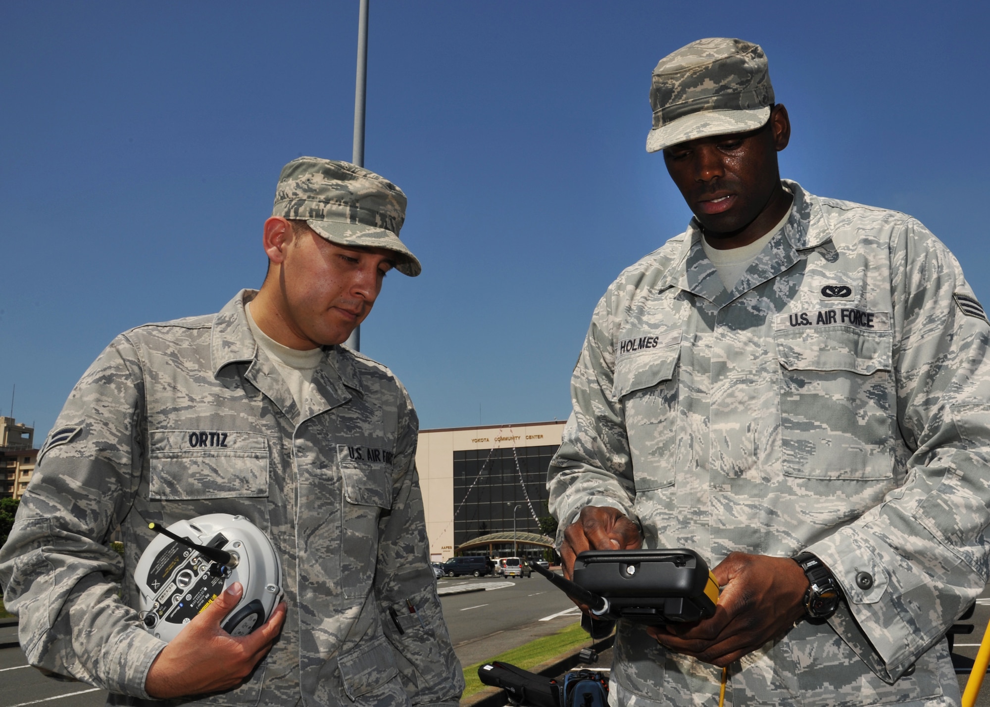 YOKOTA AIR BASE, Japan -- Airman 1st Class Carlos Ortiz (left) and Senior Airman Jason Holmes, 374th Civil Engineer Squadron engineering technicians, configure surveying equipment at Yokota Air Base, Japan, June 29, 2011. The equipment collects satellite data of the entire base by measuring elevation and the space in-between permanent objects such as buildings, barriers, and roads. (U.S. Air Force photo/Senior Airman Andrea Salazar)