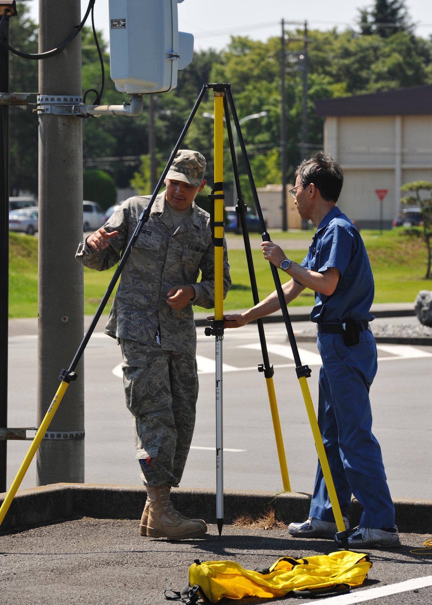 YOKOTA AIR BASE, Japan -- Airman 1st Class Carlos Ortiz (left) and Akihiko Kamijo, 374th Civil Engineer Squadron engineering technicians, set up surveying equipment June 29, 2011, at Yokota Air Base, Japan. Engineers routinely survey the base's geographical information to ensure the data is up-to-date. (U.S. Air Force photo/Senior Airman Andrea Salazar)