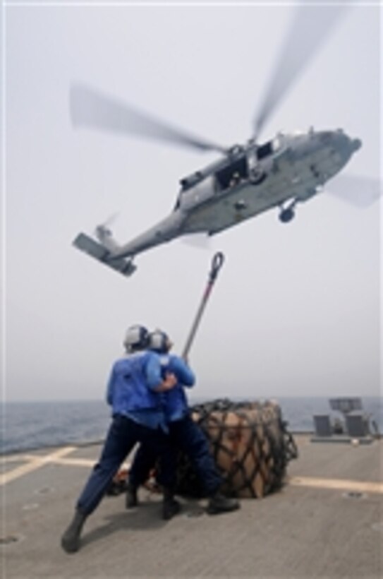 Seaman Matt Binnie (left) and Seaman Lucio Robles prepare to attach a cargo net to an MH-60S Sea Hawk helicopter during a vertical replenishment aboard the guided-missile destroyer USS Mitscher (DDG 57) in the Gulf of Oman on July 15, 2011.  The Mitscher is on deployment supporting maritime security operations and theater security cooperation efforts in the U.S. 5th Fleet area of responsibility.  