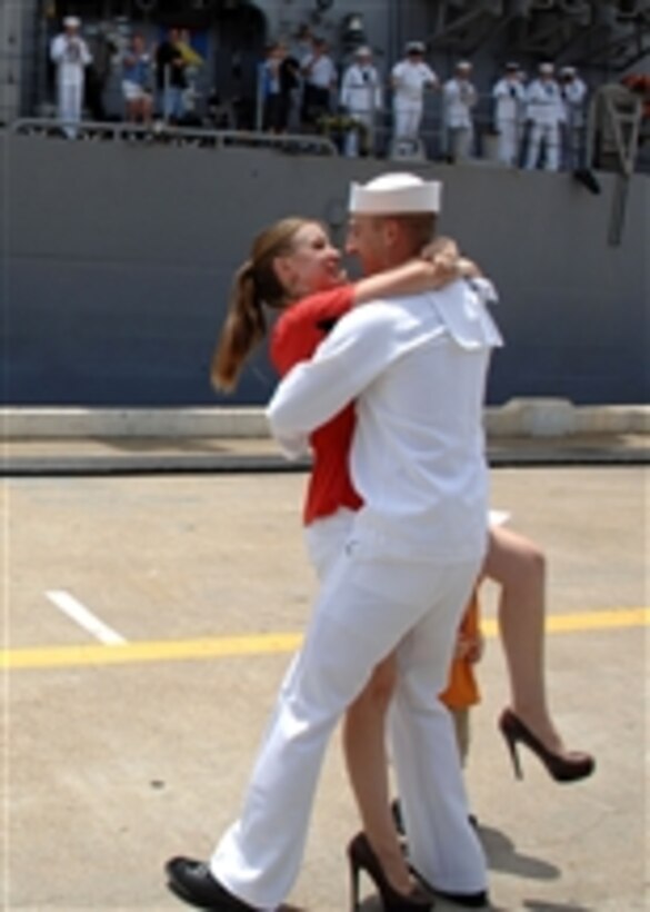 Petty Officer 2nd Class Warren Benjamin receives the traditional first kiss from his wife during a homecoming celebration for the guided-missile cruiser USS Leyte Gulf (CG 55) in Norfolk, Va., on July 15, 2011.  The Leyte Gulf returns to Naval Station Norfolk after completing a deployment to the U.S. 5th and 6th Fleet areas of responsibility.  