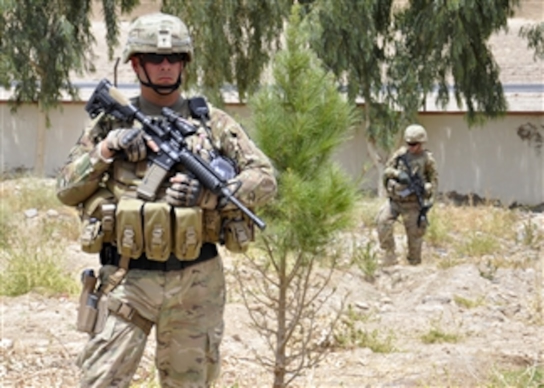 U.S. Army Sgt. Bruce Harrington (left), with the Kandahar Provincial Reconstruction Team security force, stands guard at a proposed construction site in Kandahar, Kandahar province, Afghanistan, on July 14, 2011.  The Provincial Reconstruction Team visited the site to evaluate it for the construction of truck scales needed to ensure drivers are fairly compensated and warehouse managers know how much product they have on hand.   