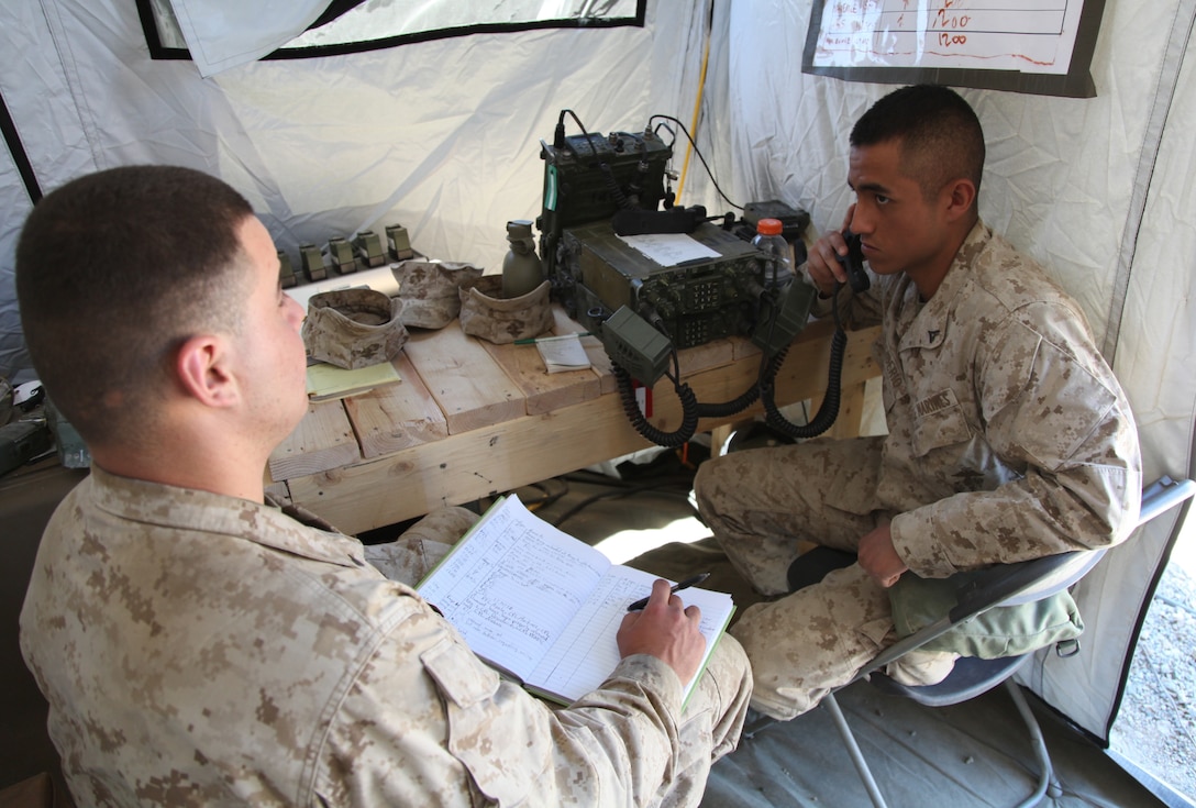 Lance Cpl. Fernando Desiderio, a data network specialist with 2nd Battalion, 24th Marine Regiment and Chicago native, mans the radio at the 2/24 Combat Operations Center as Lance Cpl. Vladimir Penev, a Chicago Heights, Ill., native who is also a data network specialist, logs transmissions, July 19. The communication component sends and receives the information required to run all aspects of an operation.