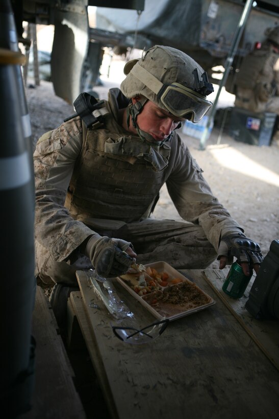 FIRE BASE SAENS, Helmand province, Afghanistan—Cpl. Stephen Palmiter, a Harrison, Idaho native takes a moment to eat his dinner in the ammunition pit of Gun-1, Alpha Battery.  Palmiter is a field radio operator and a provisional cannon crewman with 1st Battalion, 12th Marine Regiment.  The Marines who work on the gun line can sit for hours waiting while on a mission, often having to eat their meals in any spare moment they might have. (Official Marine Corps Photo by Sgt. Earnest J. Barnes)