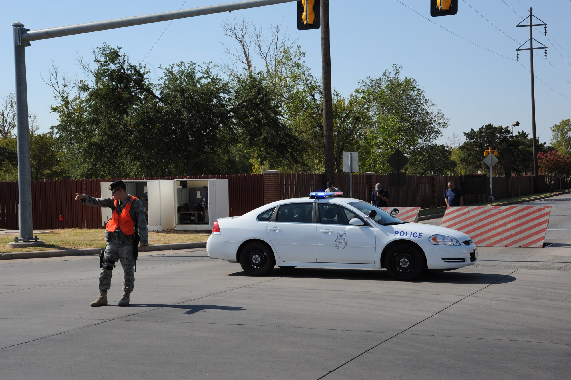 Airman 1st Class Rex Harris, 82nd Security Forces Squadron installation patrolman, directs traffic at the Sheppard Main Gate while Defense Support Services employees perform maintenance checks July 20. Every Wednesday barrier performance checks at each gate are conducted during duty hours. While one gate is closed the other two gates are open for use. (U.S. Air Force photo/Adawn Kelsey) 