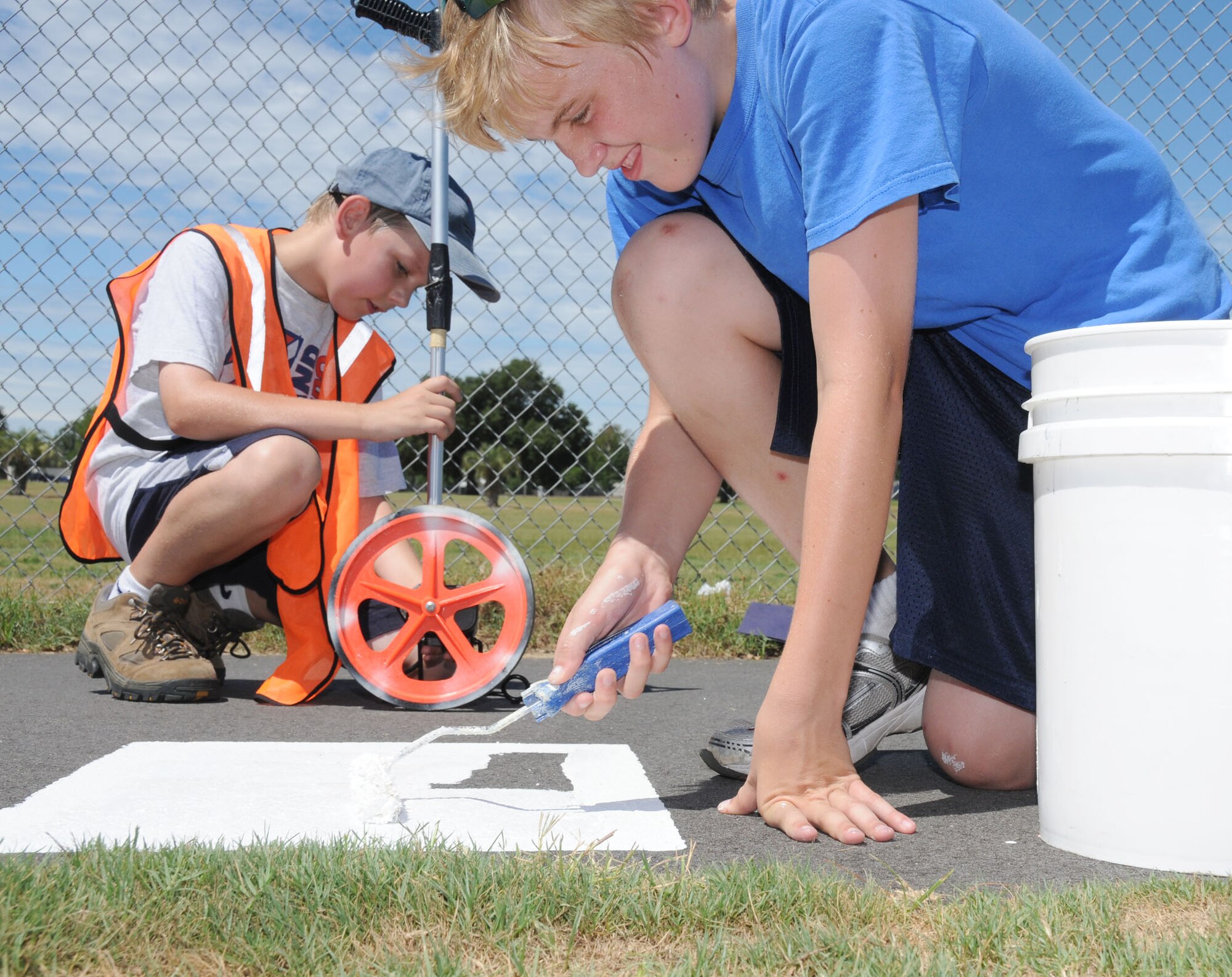 At left, Winston Downing, 11, marks every quarter mile along the I-81 track while Harrison Wright, 13, paints the mile markers.  Harrison, has taken big steps forward — literally — toward earning his Eagle Scout award with a project to mark the miles on Keesler’s tracks for the convenience of Keesler’s runners and walkers.  Winston’s parents are Col. Glen and Vicki Downing, 81st Training Wing vice commander; and Harrison is the son of Lt. Col. Jonathan and Lisa Wright, 81st Mission Support Group deputy commander.  (U.S. Air Force photo by Kemberly Groue)