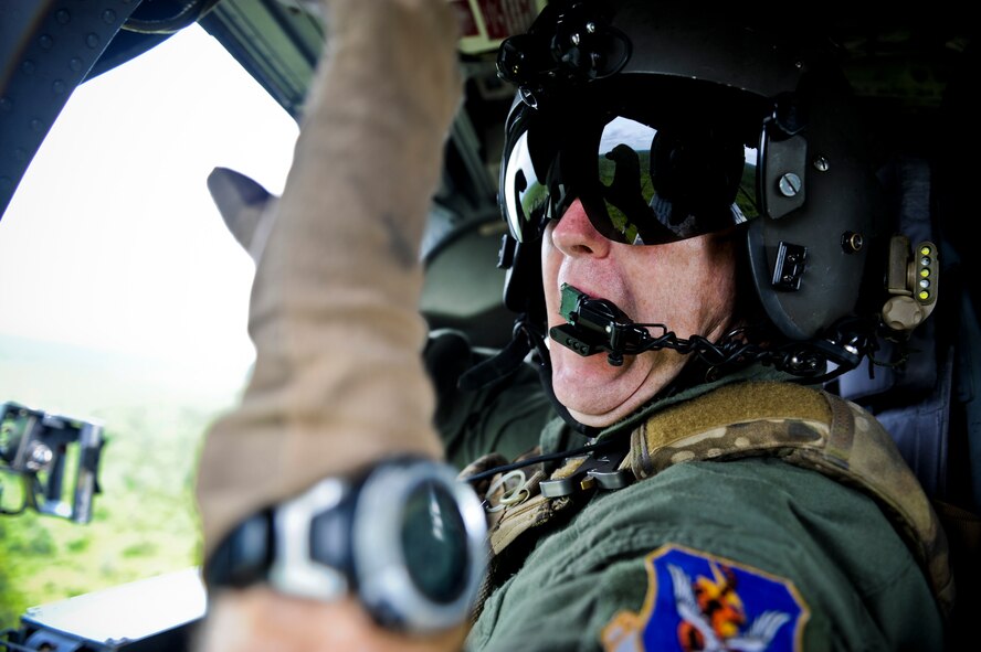 U.S. Air Force Chief Master Sgt. Scott Callahan, 41st Rescue Squadron aerial gunner, communicates with a crew member during a training mission on an HH-60G Pave Hawk over the skies of South Georgia July 12, 2011. During the training, Callahan performed various aerial gunner duties in response to simulated combat scenarios. (U.S. Air Force photo by Staff Sgt. Jamal D. Sutter/Released)