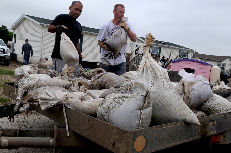 MINOT AIR FORCE BASE, N.D. -- Capt. Eddie Rubero, 5th Bomb Wing chaplain and Tech. Sgt. Lance Berentson, 741st Missile Squadron facility manager, load sandbags onto a trailer July 14. Berentson was one of the more than 1,100 Air Force Global Strike Command Airmen affected by the recent historic flooding situation, but was recently allowed back into his home. However, on arrival, he noticed their basement was flooded, their house’s foundation damaged and their yard in shambles. (U.S. Air Force photo/Airman 1st Class Jose L. Hernandez) 

