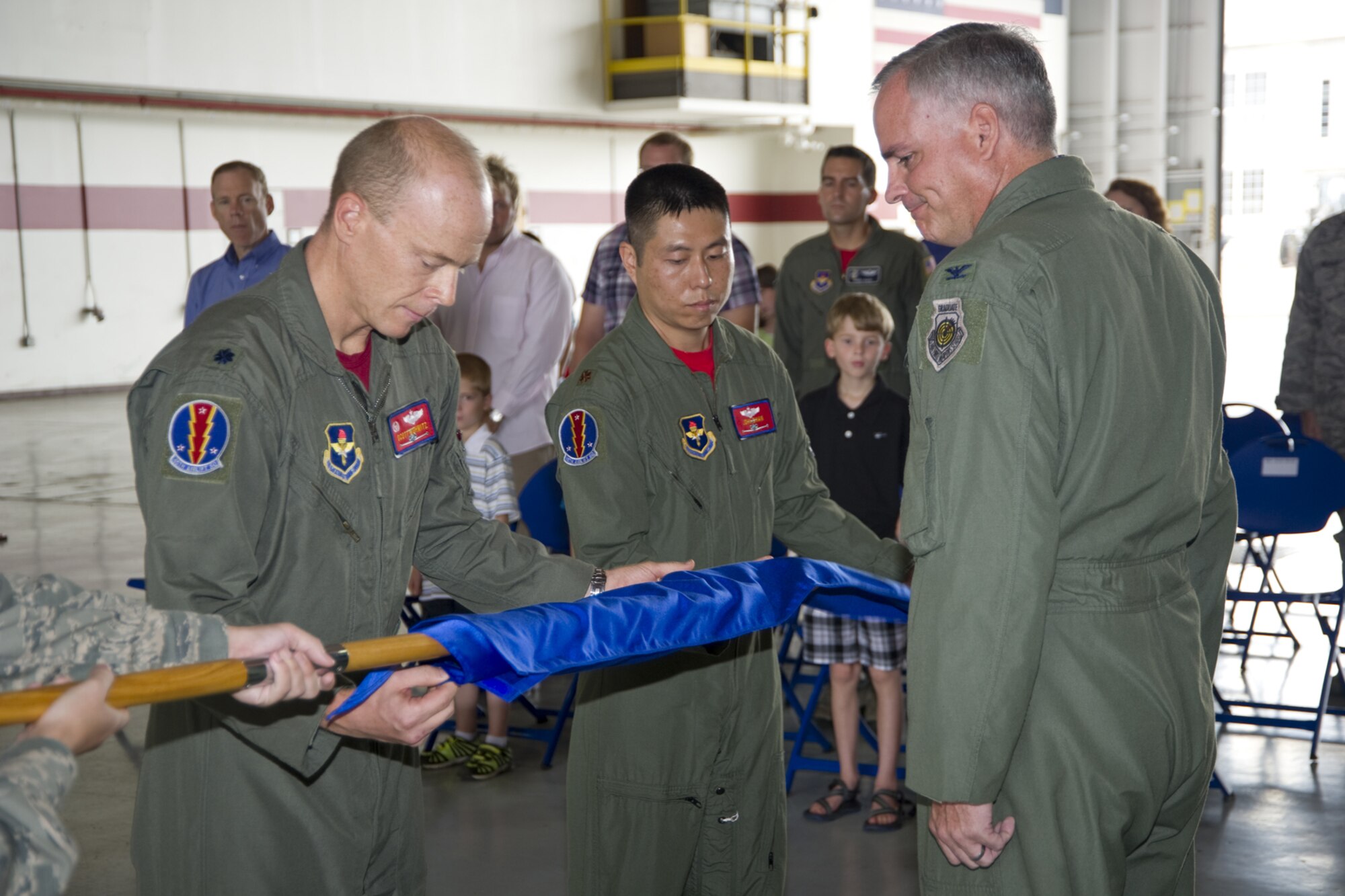 Lt. Col. Scott Nishwitz, left, 45th Airlift Squadron commander, and Major John Chan, 45th AS, slip a cover over the squadron guidon during the deactivation ceremony in Hangar 4 July 15. Col. Michael Bauer, 314th Operations Group commander, Little Rock Air Force Base, Ark., looks on. The 45th AS was a geographically-separated unit assigned to the 314th Airlift Wing at Little Rock. The last C-21 pilot instructors graduated June 24. The new C-21 schoolhouse stands up in the 458th Airlift Squadron at Scott AFB, Ill.  (U.S Air Force photo by Adam Bond)