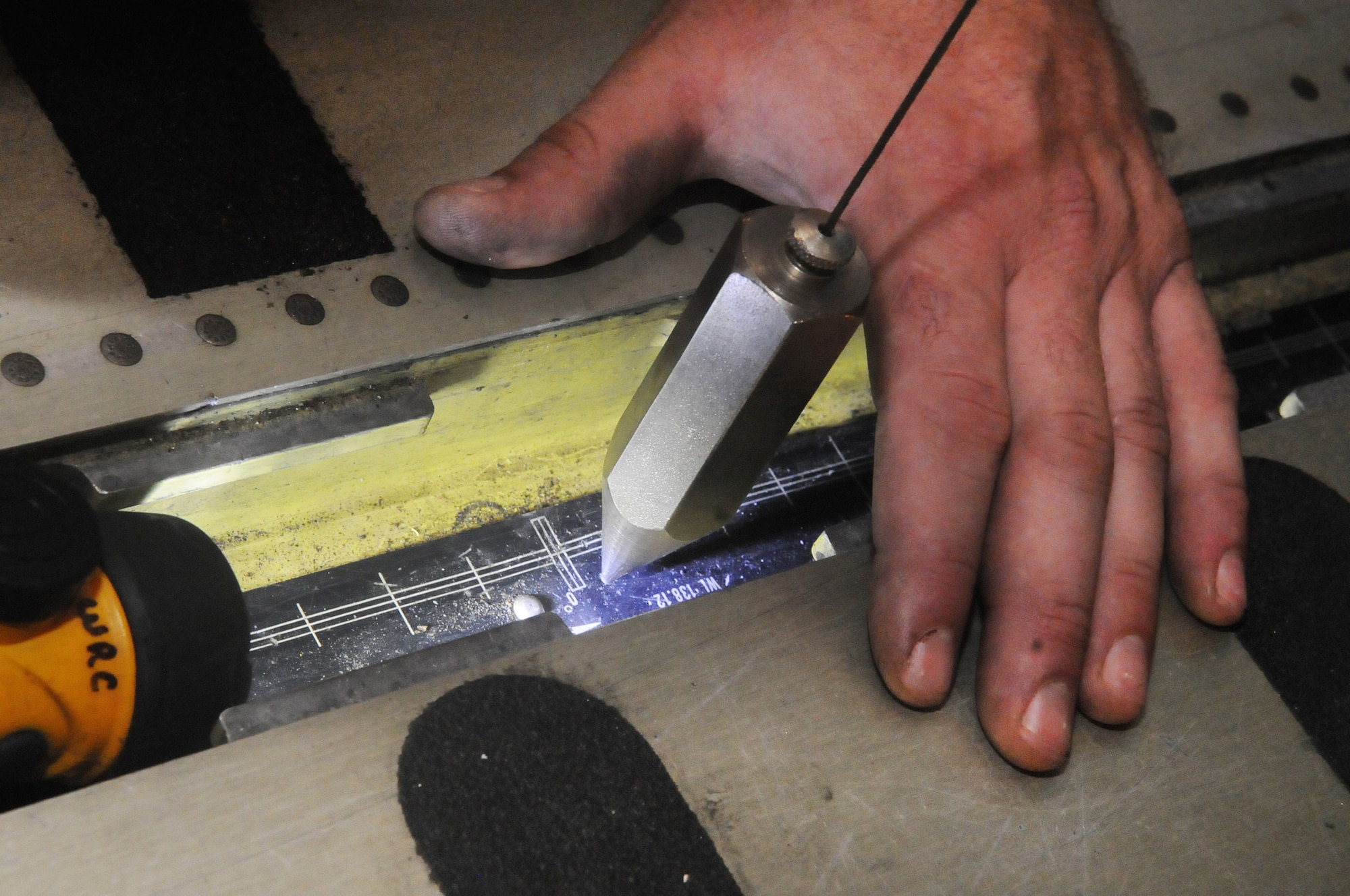 Wesley Connell uses a plumb bob over a floor gauge inside the C-5 and communicates with workers outside the aircraft in order that adjustments can be made to ensure the aircraft is level for the weighing process. U. S. Air Force photo by Sue Sapp