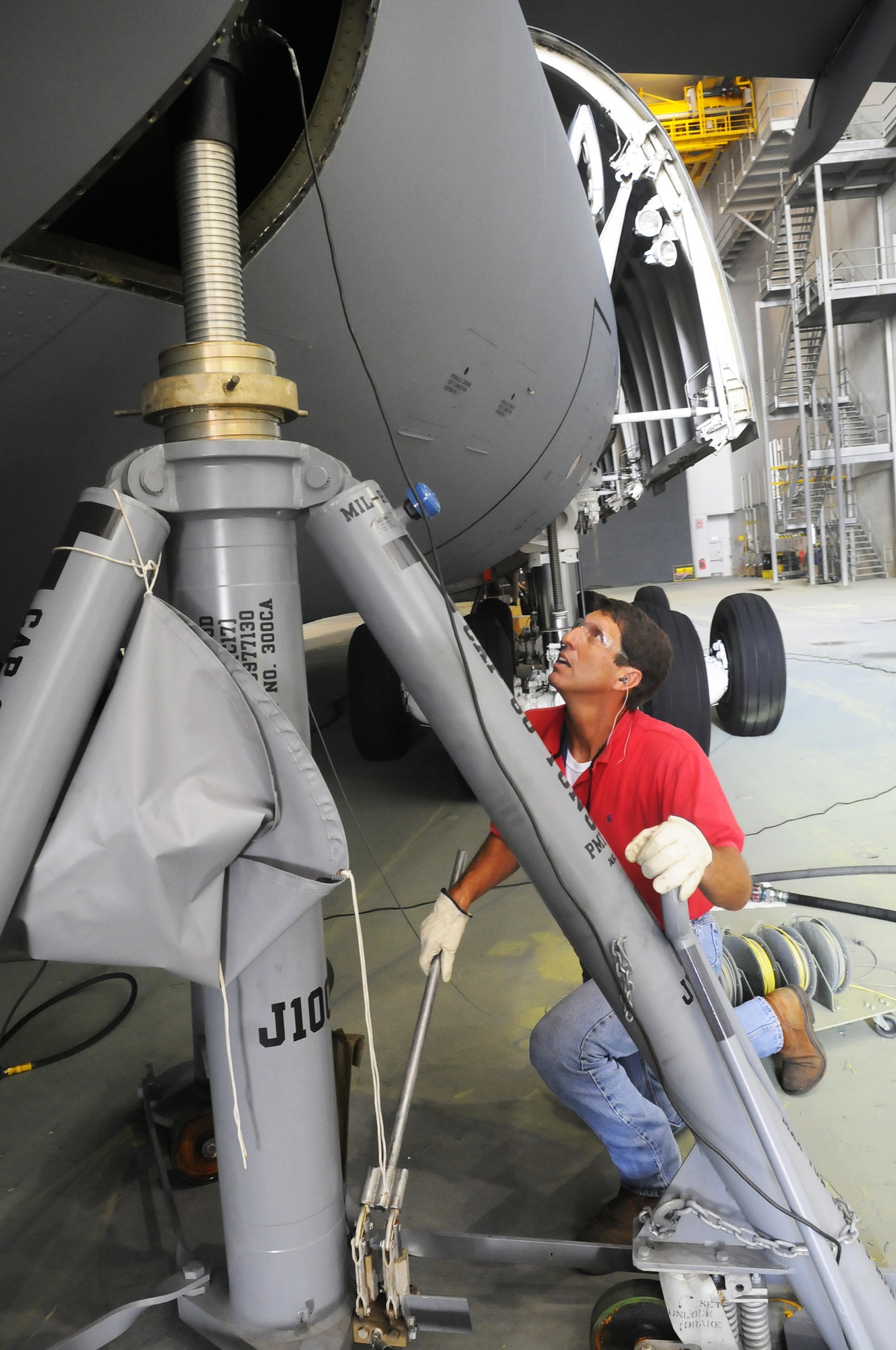 Hubert Watford uses a hand jack to level the jackstand before a C-5 is lifted for weighing. U. S. Air Force photo by Sue Sapp