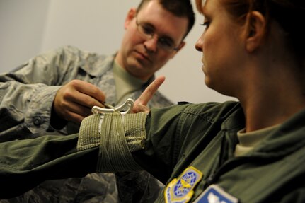 Staff Sgt.Benjamin Carter practices using an Israeli bandage on Staff Sgt. Leah Farias during the Self Aid Buddy Care portion of  circuit training July 19 at Joint Base Charleston, S.C. Farias is a loadmaster from the 17th Airlift Squadron and Carter is assigned to the 315th Maintenance Squadron.  (U.S. Air Force photo/ Staff Sgt. Nicole Mickle)