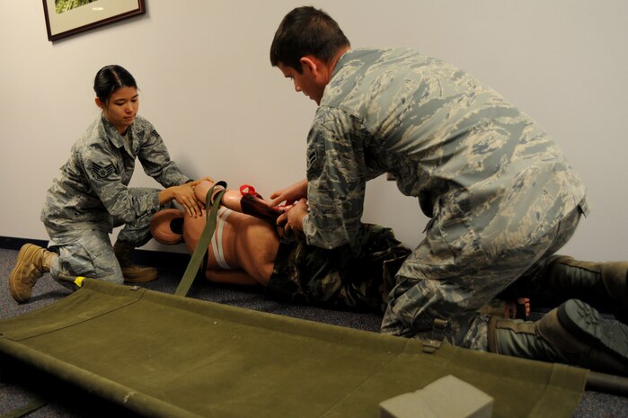 Staff Sgt.Benjamin Carter practices using an Israeli bandage on Staff Sgt. Leah Farias during the Self Aid Buddy Care portion of  circuit training July 19 at Joint Base Charleston, S.C. Farias is a loadmaster from the 17th Airlift Squadron and Carter is assigned to the 315th Maintenance Squadron.  (U.S. Air Force photo/ Staff Sgt. Nicole Mickle)