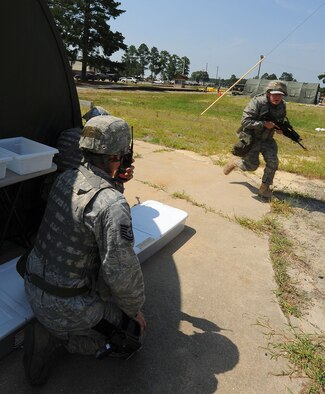 SEYMOUR JOHNSON AIR FORCE BASE, N.C. -- Tech. Sgt. Elmer Smith, 4th Security Forces Squadron flight sergeant, radios orders while Airman 1st Class Joseph Kacynski, 4th SFS patrolman, runs for cover during a phase II operational readiness exercise here July 19, 2011. Security forces Airmen are responsible for base security. (U.S. Air Force photo/Senior Airman Gino Reyes)(RELEASED)
