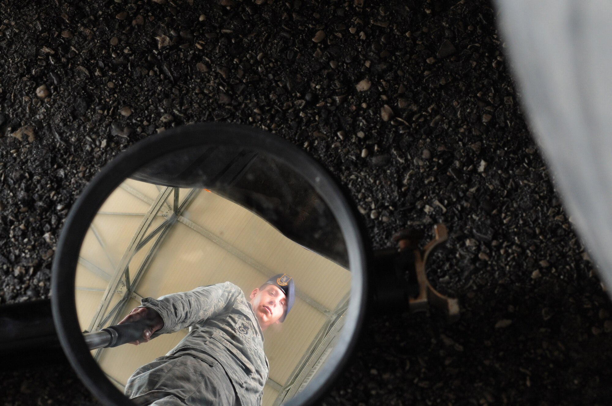 Airman 1st Class William Lott, 31st Security Forces Squadron contractor inspection team member, checks a contractor vehicle's undercarriage July 15 at Aviano Air Base's larger vehicle inspection station. An inspection team consists of five members to make sure the inspection process runs smoothly and the vehicles are inspected thoroughly.(U.S. Air Force photo/Airman LaVel Sterling)