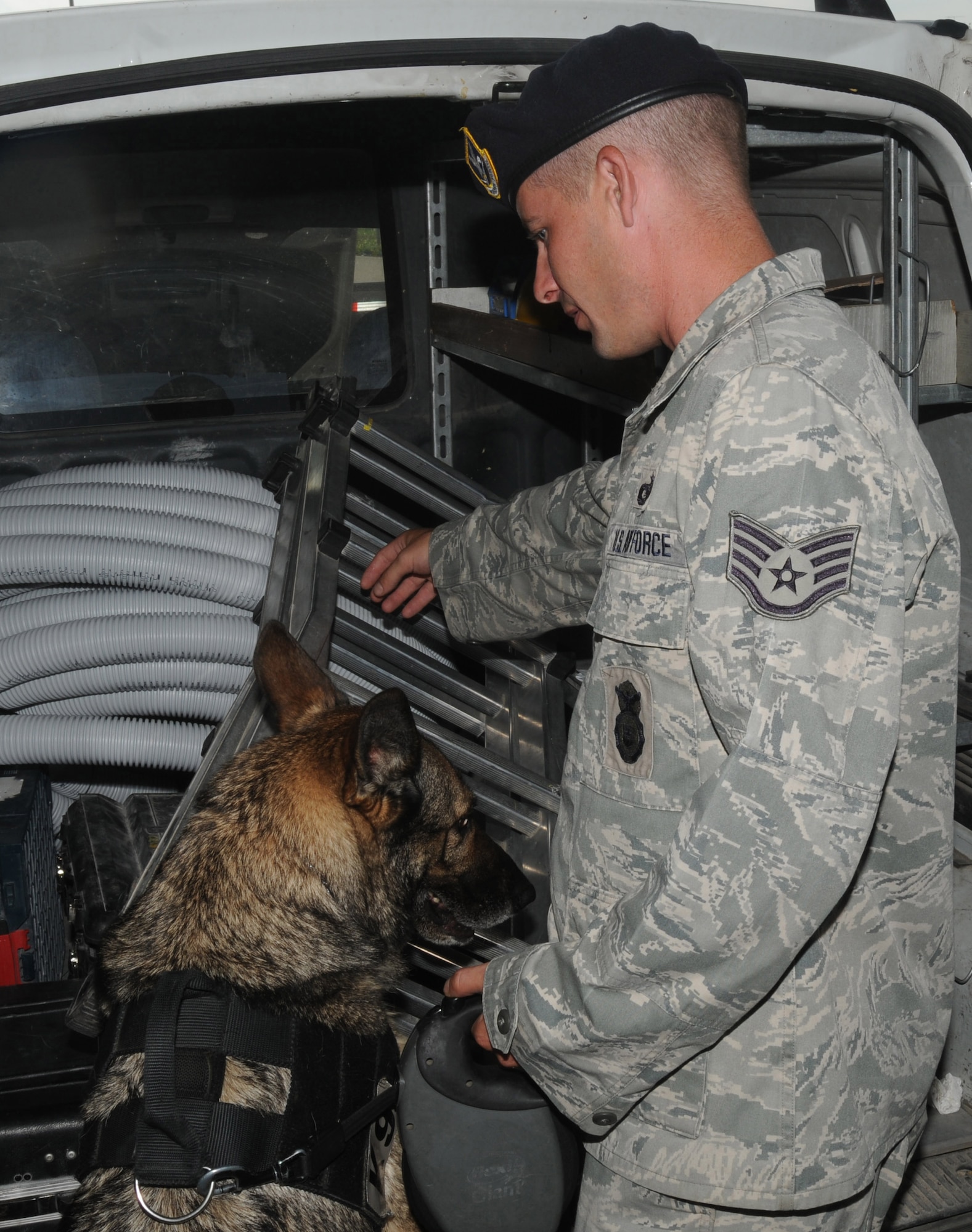 Staff Sgt. Kevin Mahana, 31st Security Forces Squadron military working dog handler,  and MWD Treesje search a contractors vehicle July 15 at Aviano Air Base?s larger vehicle inspection station gate. Military working dogs and their handlers search all incoming contractor vehicles for explosives and weapons to ensure base security.(U.S. Air Force photo/Airman LaVel Sterling)