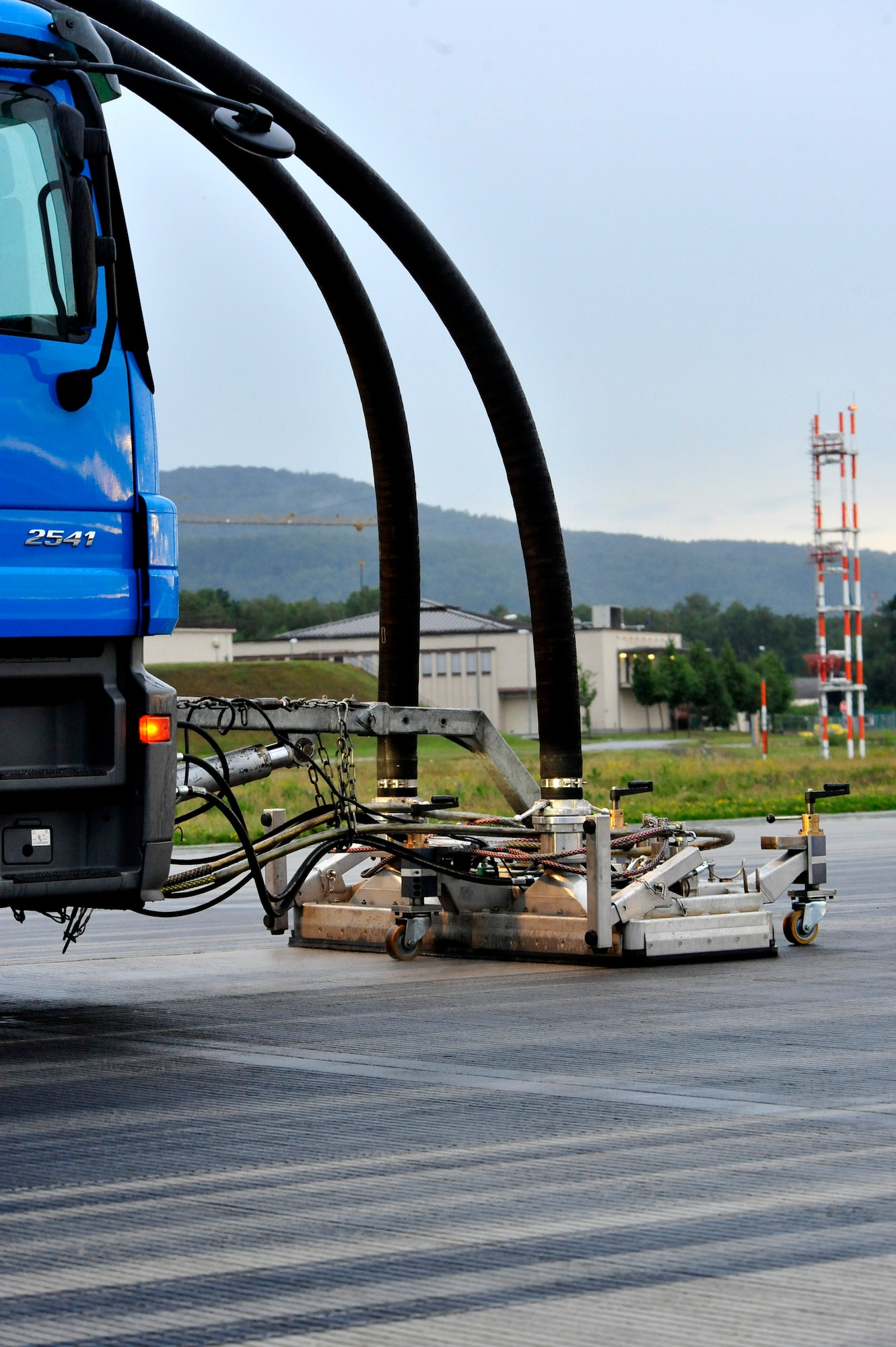 Contractors from Strate Wasserhochdrucktechnick e.K. remove excess rubber deposits from the runway to prevent aircraft from sliding off when they land, July 19, 2011, Ramstein Air Base, Germany.  The weeklong project cost $91K.  (U.S. Air Force Photo by Tech. Sgt. Chenzira Mallory)
