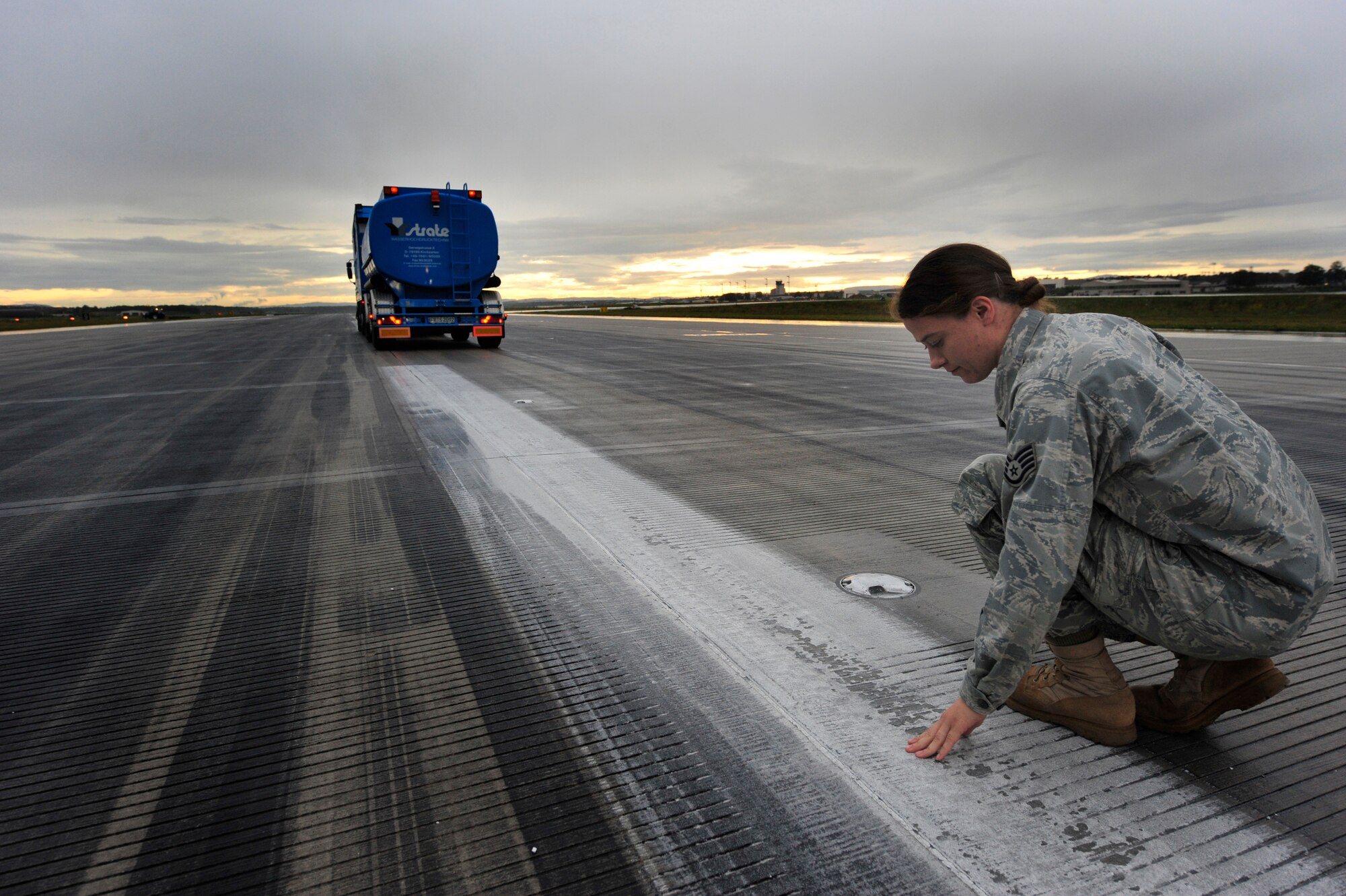 Staff Sgt. Stephanie Heck, Airfield Management Operations NCOIC, checks the amount of rubber and paint removed from the runway after the Wasserhochdrucktechnick makes its first pass, July 19, 2011, Ramstein Air Base, Germany.  Contractors from Strate Wasserhochdrucktechnick e.K removed excess rubber from various parts of the runways to prevent aircraft from sliding when they land.  The weeklong project cost $91K.  (U.S. Air Force Photo by Tech. Sgt. Chenzira Mallory)