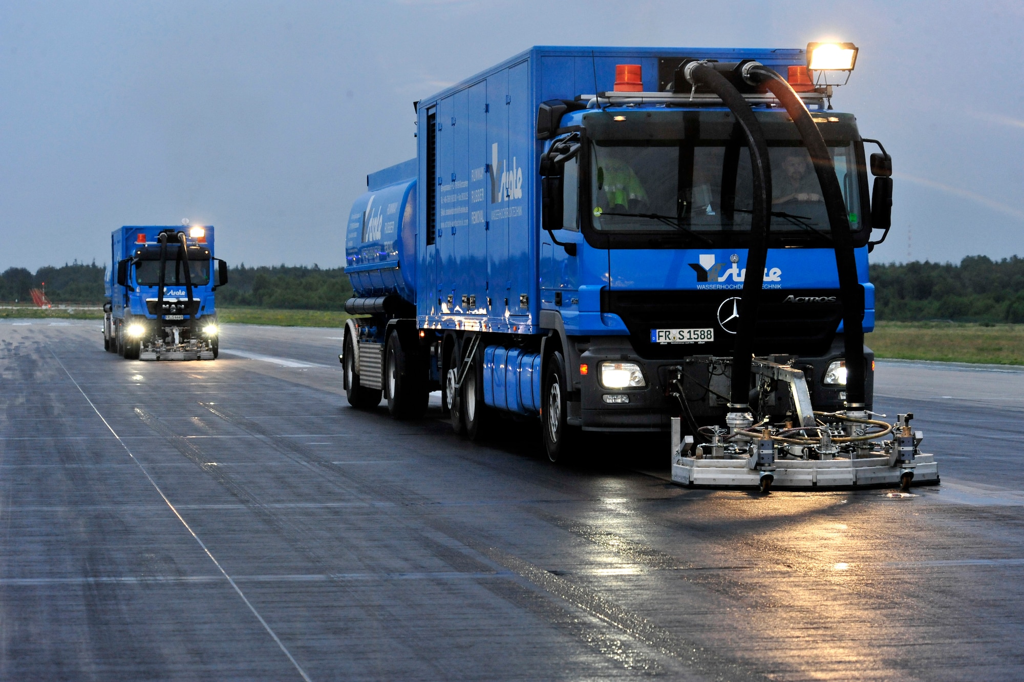 Contractors from Strate Wasserhochdrucktechnick e.K. remove excess rubber deposits from the runway to prevent aircraft from sliding off when they land, July 19, 2011, Ramstein Air Base, Germany.  The weeklong project cost $91K.  (U.S. Air Force Photo by Tech. Sgt. Chenzira Mallory)