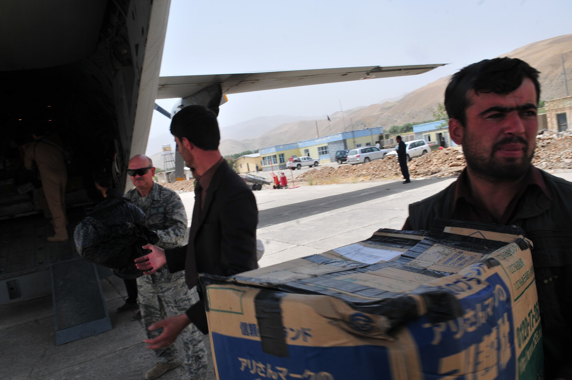 Chaplain (Maj.) Larry Henderson, 438th Air Expeditionary Wing senior chaplain, delivers school supplies on the flight line to school representatives in Badakhshan province July 19.  The supplies were delivered to the capital city of Faizabad by a mixed C-27 Afghan Air Force and coalition crew from the AAF compound Kabul, Afghanistan.  Mr. Jan Agha, of North Eastern Afghanistan Schools, Central Asia Institute, worked with officials at the 438th Air Expeditionary Wing to have the supplies delivered.  (U.S. Air Force photo by Tech. Sgt. Brian E. Christiansen)