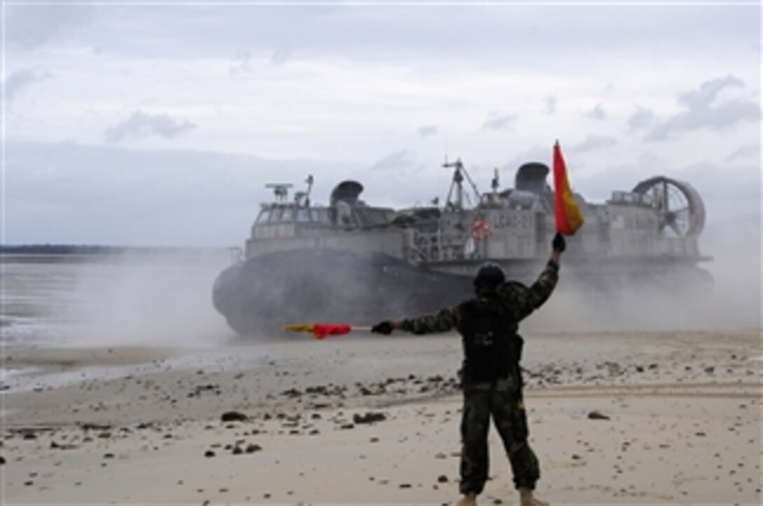 A U.S. Navy sailor with Beachmaster Unit 1 directs a landing craft, air cushion toward the beach during a water transport exercise with the Australian Army at Shoalwater Bay Military Training Area in Queensland state, Australia, during Talisman Sabre 2011 on July 15, 2011.  Talisman Sabre is a combined biennial exercise between the U.S. and Australian militaries designed to enhance both nations' ability to respond to regional contingencies.  