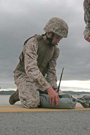 Lance Cpl. Andrew P. Suarez, a Marine Air Control Squadron::r::::n::4 Detachment Bravo air traffic controller, secures a light to a::r::::n::sandbag as part of training for the Marine Air traffic Control::r::::n::Mobile Team at the station flight line here July 21. Red lights::r::::n::served as the departure point. The green lights marked were to land and white lights served as the runways borders.