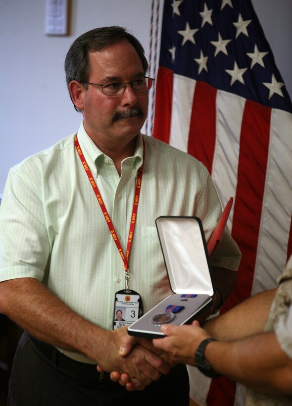 Dennis Douthett, the II MEF training officer, is awarded the Navy Meritorious Civilian Service Medal, July 21, 2011, aboard Marine Corps Base Camp Lejeune, N.C. For almost a decade, Douthett has worked with the II MEF Communications Security Office, which works to protect our nation’s secrets from our adversaries.