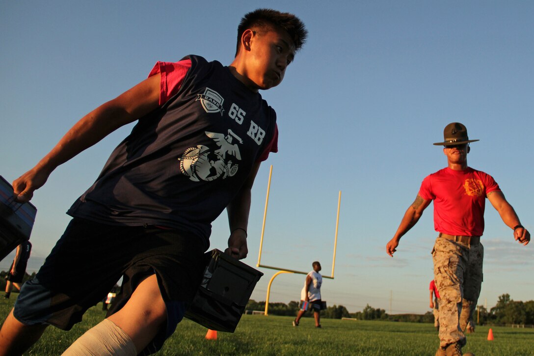 A drill instructor motivates an athlete attending the Minneapolis Junior Rank Diamond Flight Football Camp to increase his speed during an ammo can exercise July 21. Several Marines from Recruiting Station Twin Cities attended the three-day camp to share their core values of honor, courage and commitment and promote academic and athletic excellence. For additional imagery from the event, visit www.facebook.com/rstwincities.