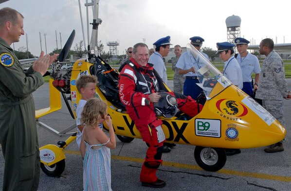 Col. Corey Martin, 18th Wing vice commander, applauds Norman Surplus, an autogyro pilot from Larne, County Antrim, Northern Ireland, as he steps out of his MT-03 autogyro after landing at Kadena Air Base, Japan,  July 20. Surplus is making the first autogyro world record attempt to circumnavigate the globe. "The 8.5-hour flight from the Philippines to Kadena was the longest and most demanding flight of the expedition because it was over water," said Martin. "I only saw two ships during my flight." (U.S. Air Force photo/ Airman 1st Class Tara A. Williamson)