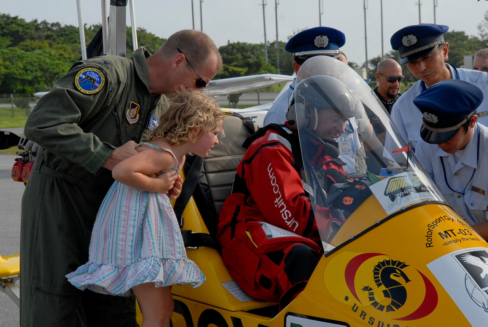 Col. Corey Martin, 18th Wing vice commander, gives his daughter, Amelia, a better view of the inside of the MT-03 autogyro piloted by Norman Surplus from Larne, County Antrim, Northern Ireland, that landed July 20 at Kadena Air Base, Japan. Surplus and his autogyro, 'Roxy', are making the first world record attempt at a circumnavigation of the globe in an autogyro. (U.S. Air Force photo/ Airman 1st Class Tara A. Williamson)