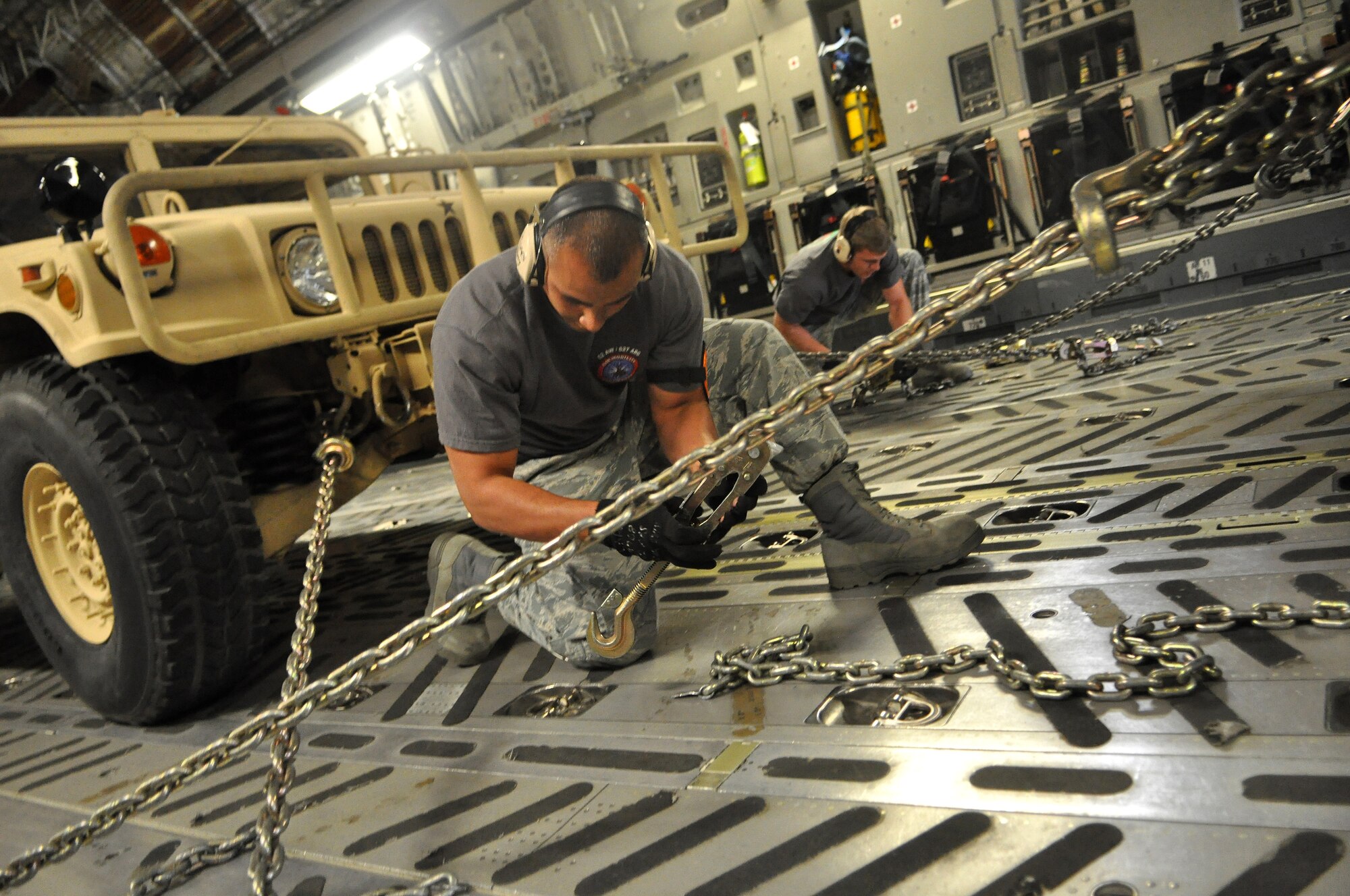 Staff Sgt. Jason Caro, 62nd Aerial Port Squadron Rodeo Team captain, left, and Airman 1st Class Brad Bardsley, 62nd APS Rodeo Team member, tighten chains to restrain a K-loader aboard a C-17 Globemaster III during Rodeo training July 19 at Joint Base Lewis-McChord, Wash. The team has been preparing for Rodeo since May with daily training scenarios and early morning workouts. Rodeo, sponsored by the Air Mobility Command, is the Mobility Air Force's readiness competition. This competition focuses on improving worldwide air mobility forces' professional core abilities. (U.S. Air Force photo/Airman 1st Class Leah Young)