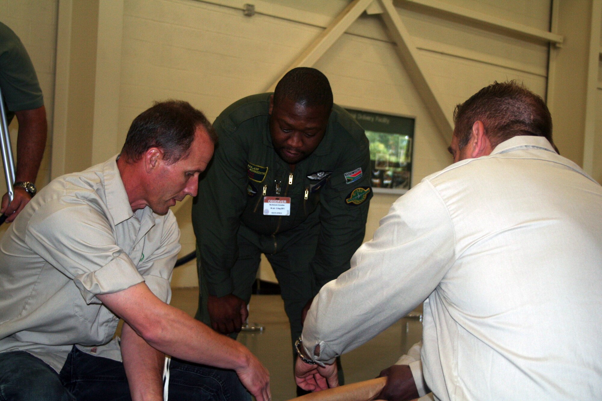 Maj. Ntuluzelo Kereeditse of the South Africa air force observes parachute riggers pack a parachute at the 62nd Aerial Port Squadron aerial delivery facility July 21, 2011, at Joint Base Lewis-McChord, Wash. Kereeditse was one of several participants from five African nations in the 2011 International Airdrop Symposium July 19-21, 2011. (U.S. Air Force Photo/Master Sgt. Scott T. Sturkol)