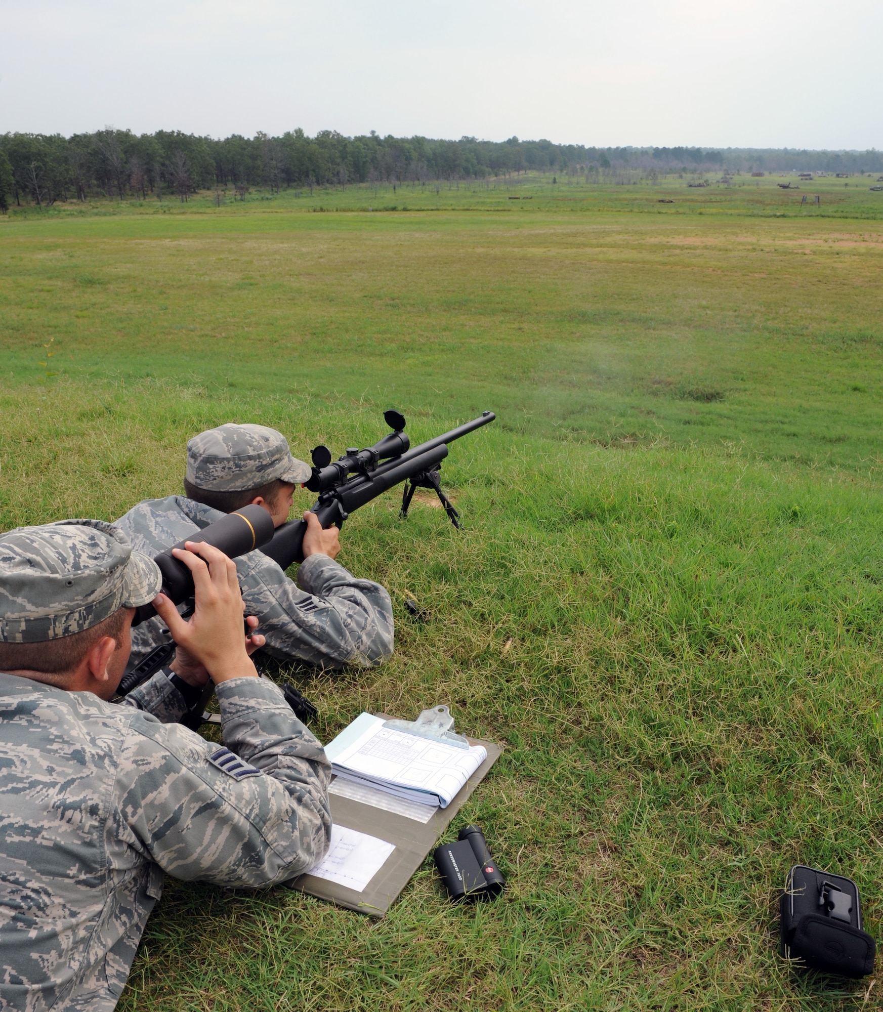 Senior Airman Timothy Collar (right), a 19th Security Forces Squadron trainer, shoots at a target July 7, 2011, at Camp Robinson, Ark., as Staff Sgt. Carl Hook, a 19th SFS trainer, traces the round during advanced designated marksman training in preparation for the Air Mobility Command RODEO. ADM is one of three different events that SFS members participate in this year’s competition. (U.S. Air Force photo by Airman 1st Class Rusty Frank)