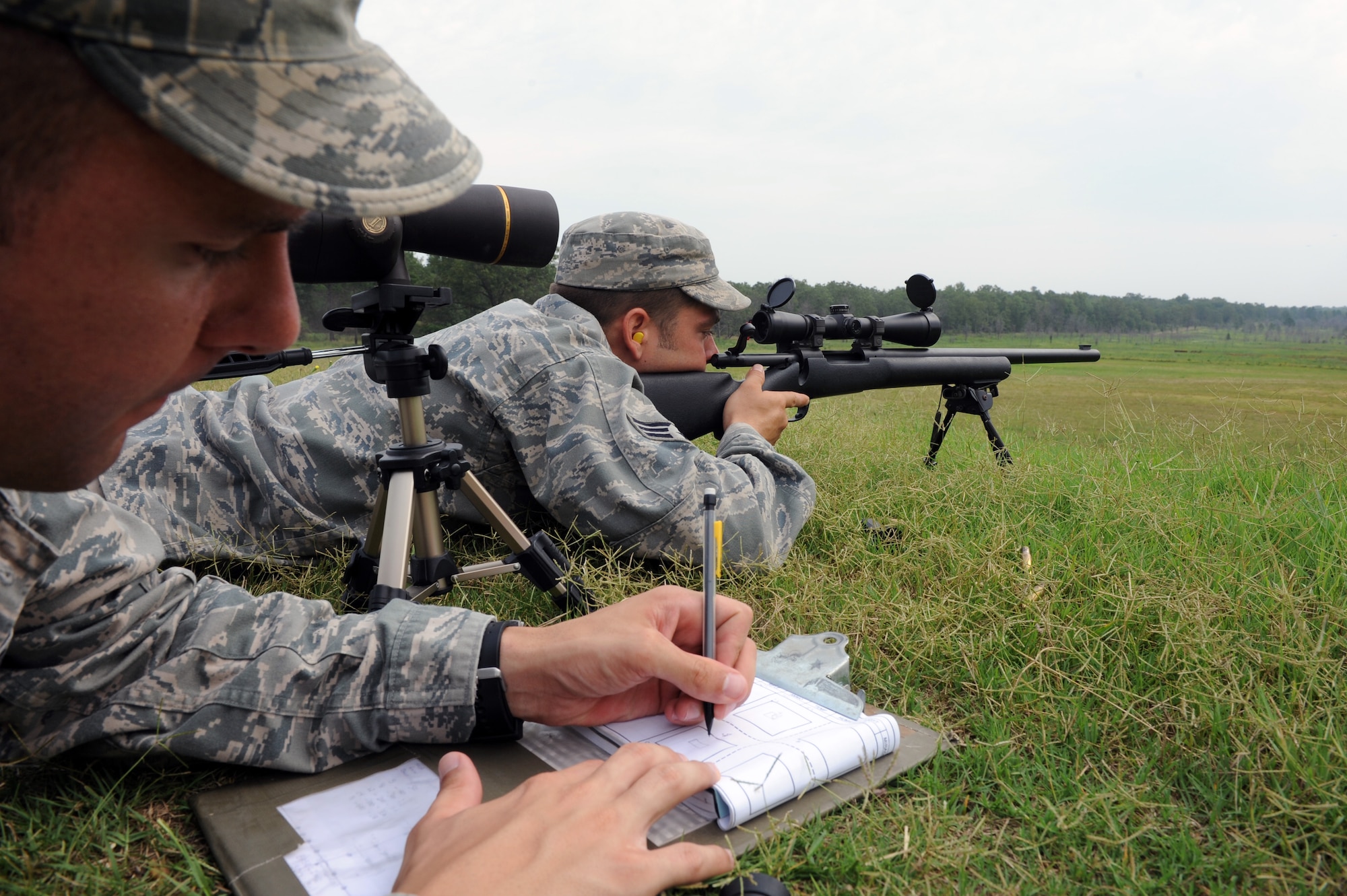 Staff Sgt. Carl Hook, a 19th Security Forces Squadron trainer, fills out his data book, as Senior Airman Timothy Collar, a 19th SFS trainer, prepares to fire the M-24 rifle July 7, 2011, at Camp Robinson, Ark., during advanced designated marksman training in preparation for the Air Mobility Command RODEO. ADM is one of three different events that SFS members participate in this year’s competition. (U.S. Air Force photo by Airman 1st Class Rusty Frank)