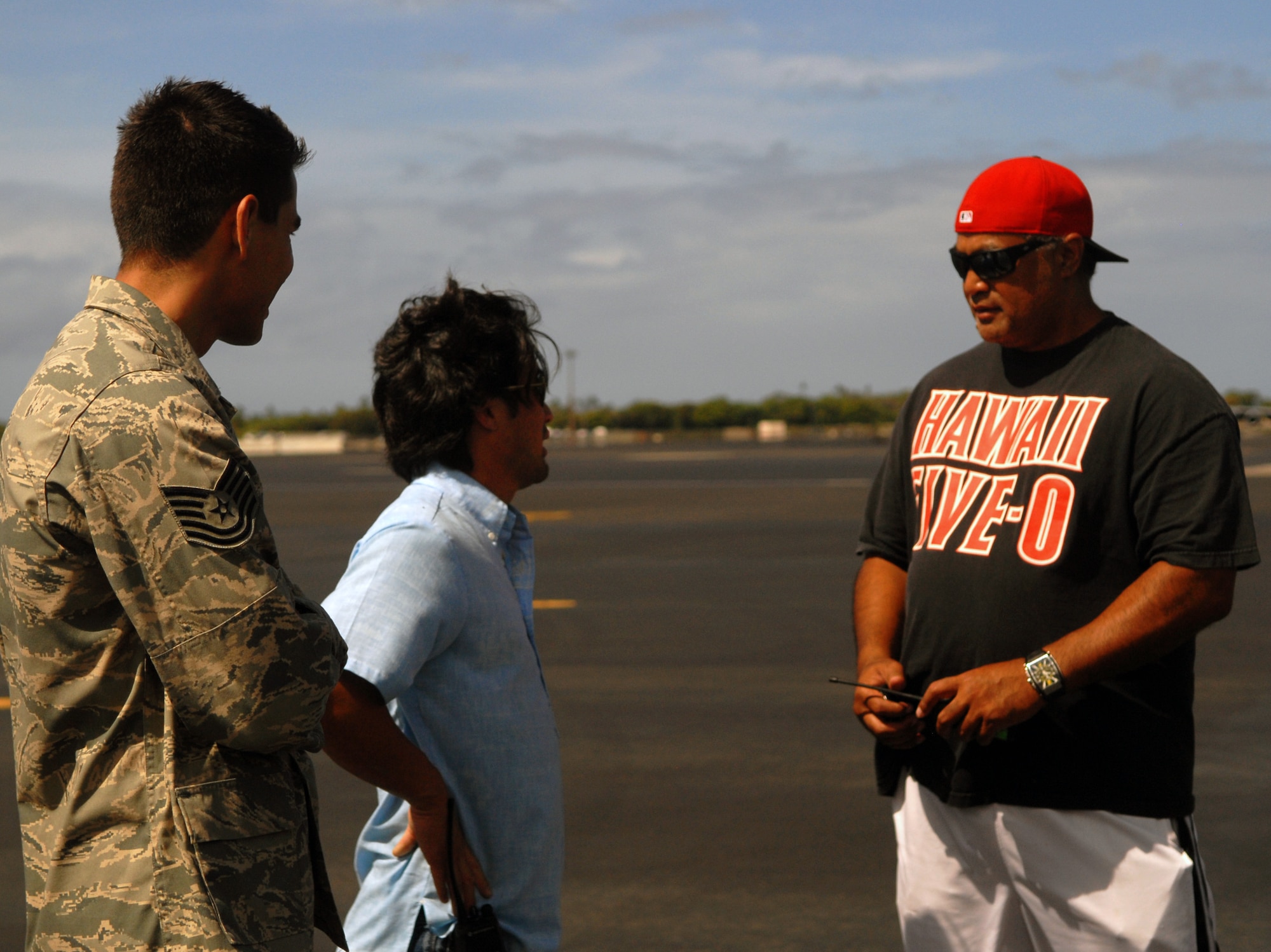 Tech. Sgt. Anthony Gomez, left, a Public Affairs specialist for the 15th Wing, talks with members of the production crew of "Hawaii Five-0" on the flight line at Joint Base Pearl Harbor-Hickam, Hawaii, July 20. Ten Airmen participated in the shoot, doing their day-to-day jobs, and now have a chance to be in the final shots. (U.S. Air Force photo/Staff Sgt. Carolyn Herrick)