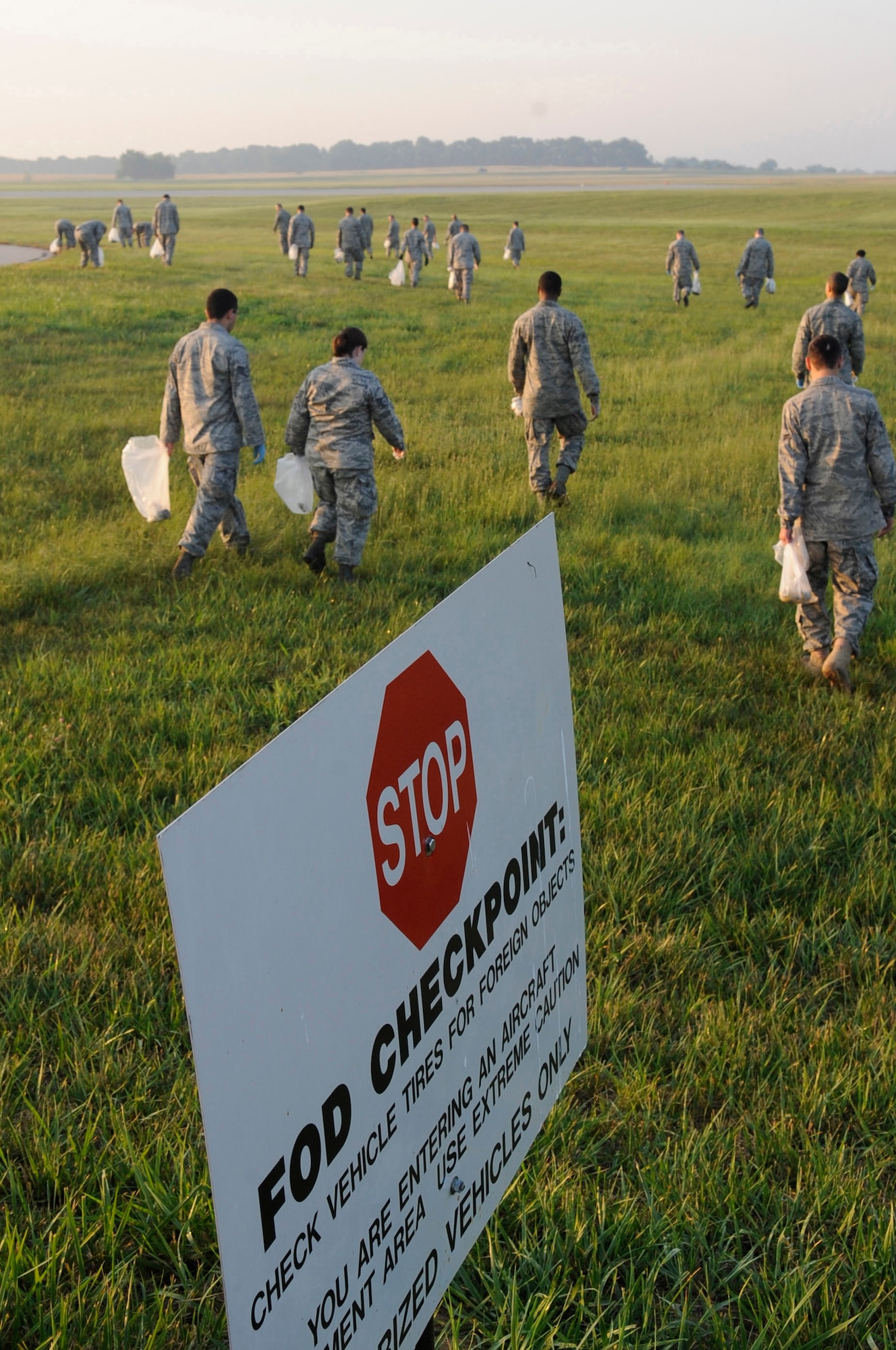 WHITEMAN AIR FORCE BASE, Mo. ? Members of Whiteman Air Force Base, Mo. performs a foreign object debris walk on the flightline collecting more than 200 pounds before starting the day, July 15. Since FOD is mostly made up of small rocks and pebbles, it is hard to remove the debris with sweeper trucks, so Airman have to physically remove the FOD themselves by lining up side-by-side and walking across the flightline. (U.S. Air Force photo by Senior Airman Alexandra M. Boutte) (RELEASED)