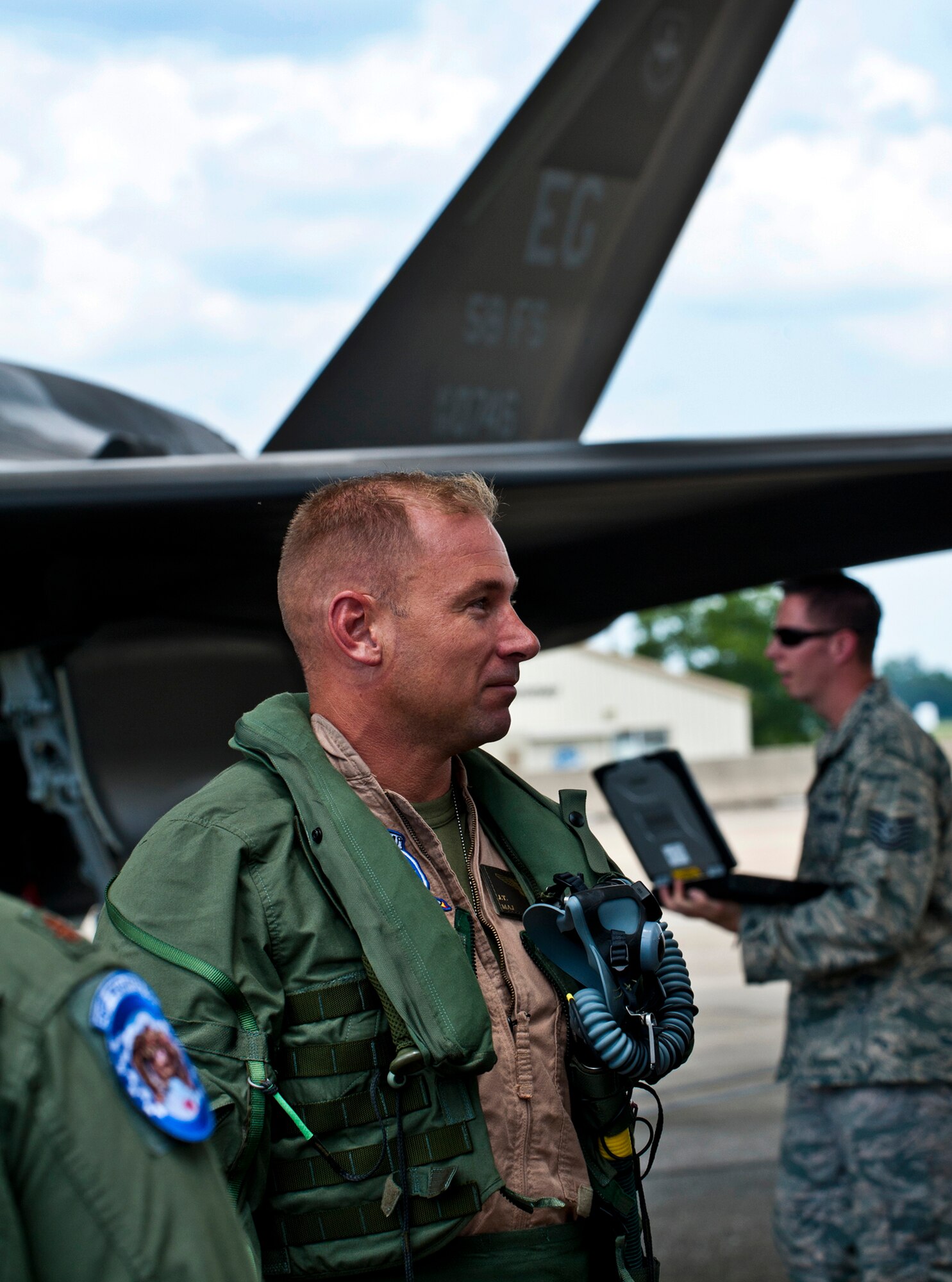 Marine Maj. Joseph Bachmann, of the 33rd Operations Group, relaxes with 33rd Fighter Wing leadership as maintainers secure the newest F-35 Lightning II joint strike fighter to arrive at Eglin Air Force Base, Fla., July 20.  Bachmann is the first Marine pilot to be JSF certified and AF-8 is the second aircraft to arrive to the 33rd Fighter Wing.  (U.S. Air Force photo/Samuel King Jr.)